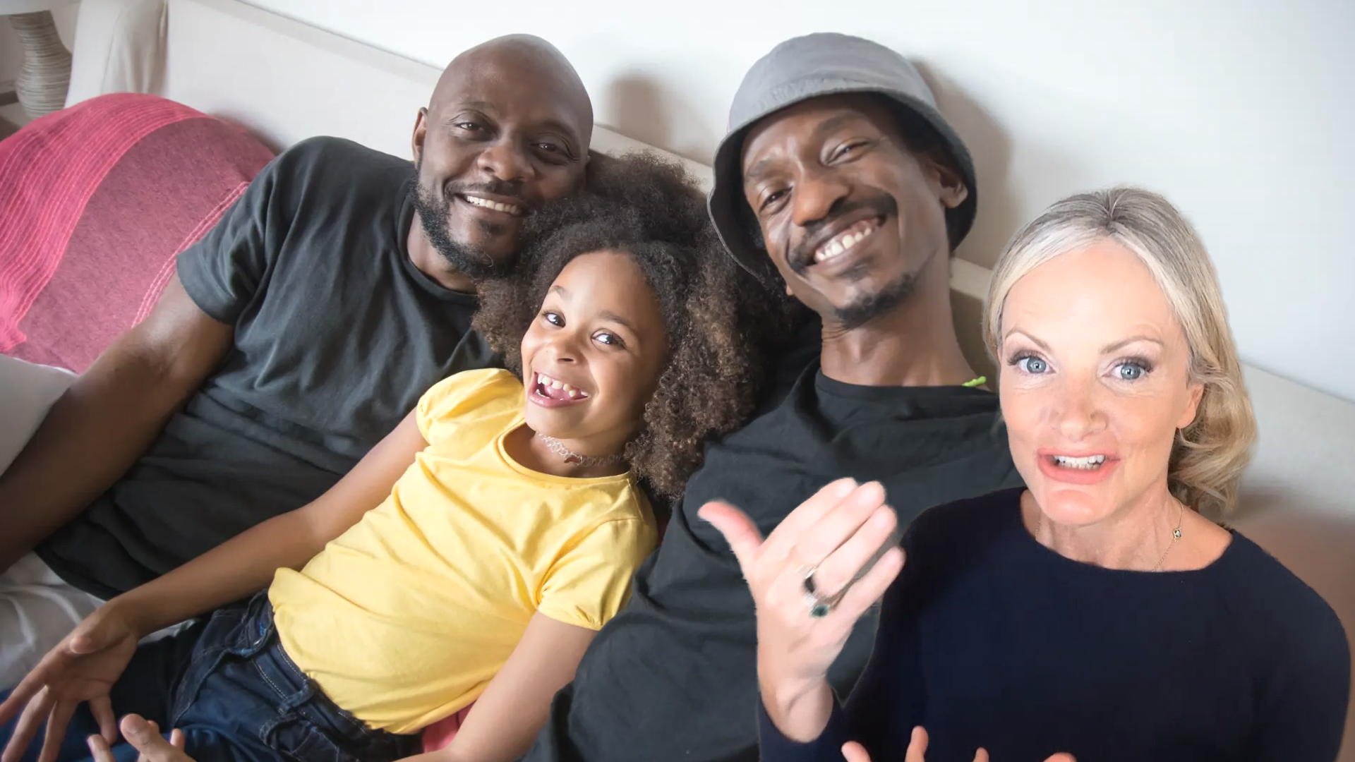 Diverse group of adults and a child sitting together on a sofa and smiling at the camera, representing connection, relationships and family life within neuro-unique families.