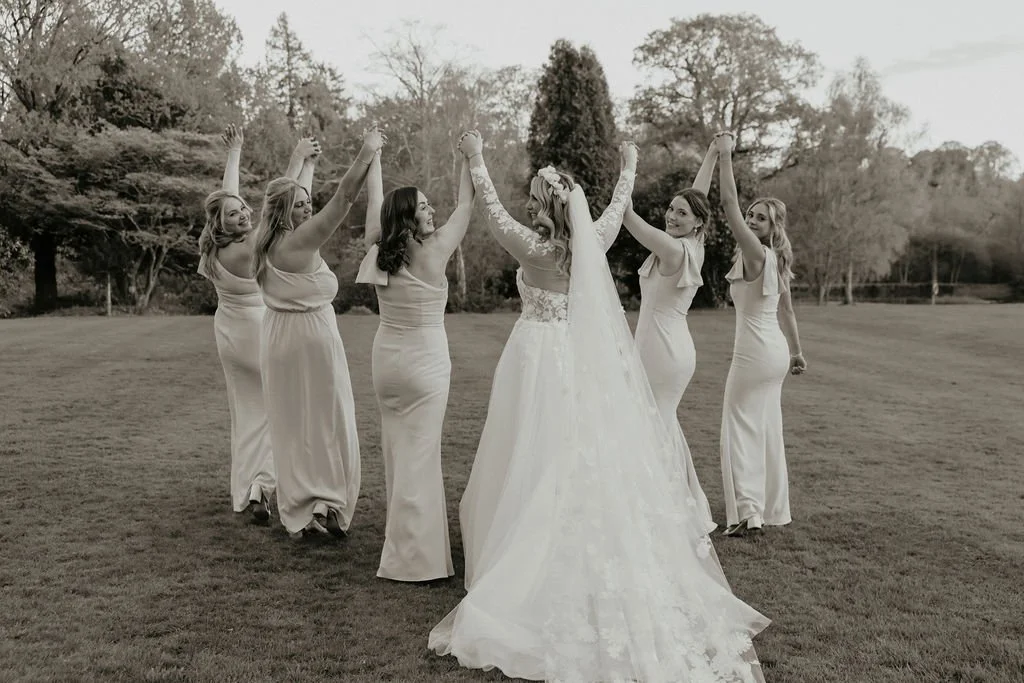 Bride & bridesmaid with arms in the air having fun