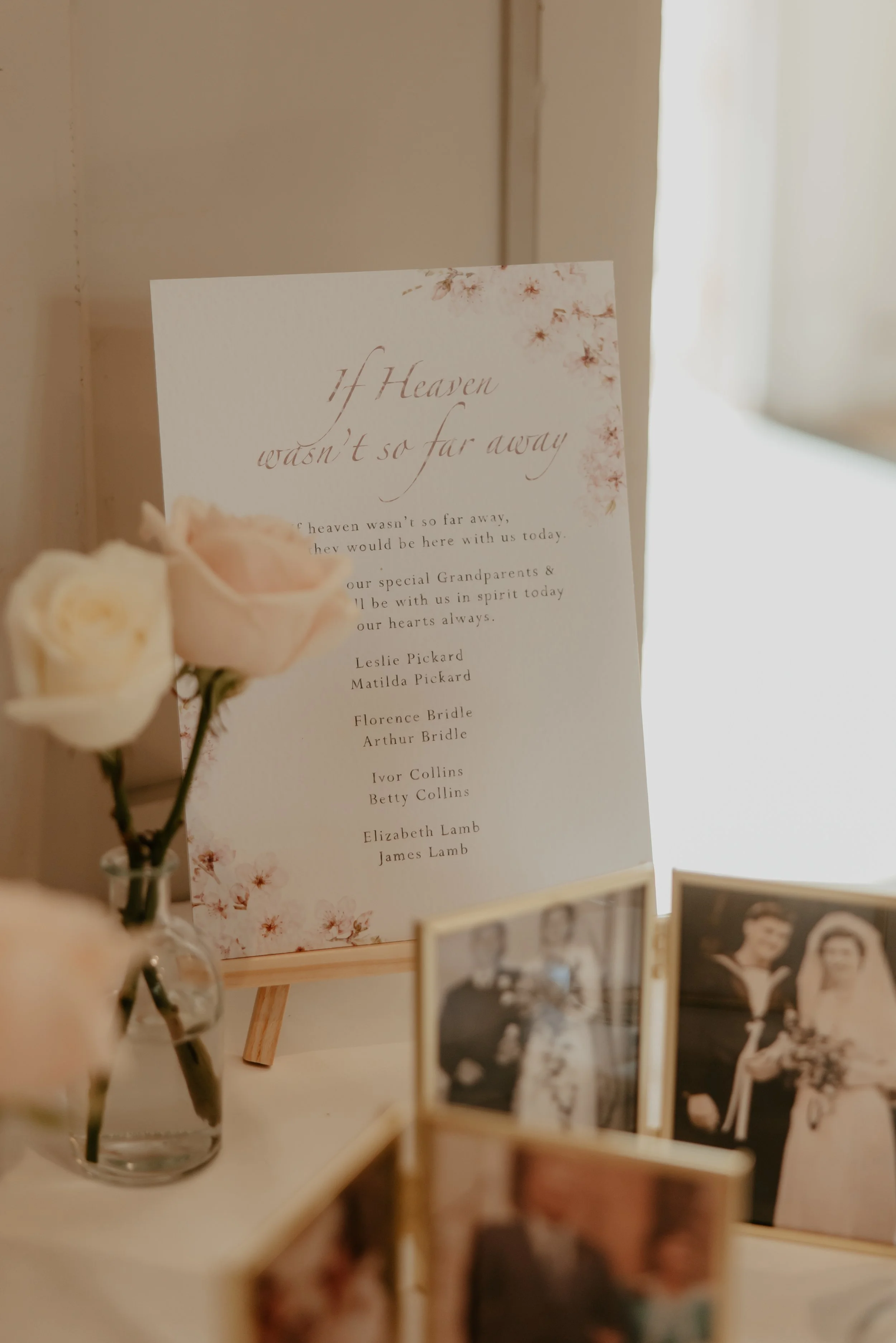 A memorial display with a poem titled 'If Heaven wasn't so far away,' surrounded by framed photos of a wedding and flowers.