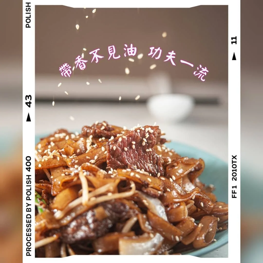 A dish of stir-fried noodles with beef and vegetables topped with sesame seeds, in a blue bowl. Overlaid text in Chinese characters.