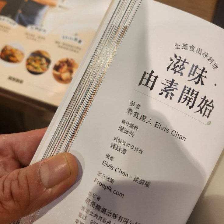 A menu page in Chinese with the title 'Vegetarian Beginning' and the name Elvis Chan mentioned as the author, with a background showing another menu with pictures of dishes.