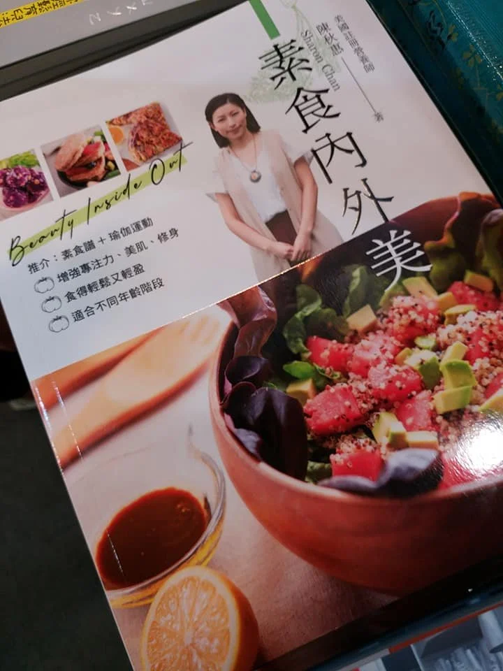 A Chinese book or magazine about healthy eating and beauty with a woman standing on the cover, featuring images of healthy foods like salad, lemon, and dressing.