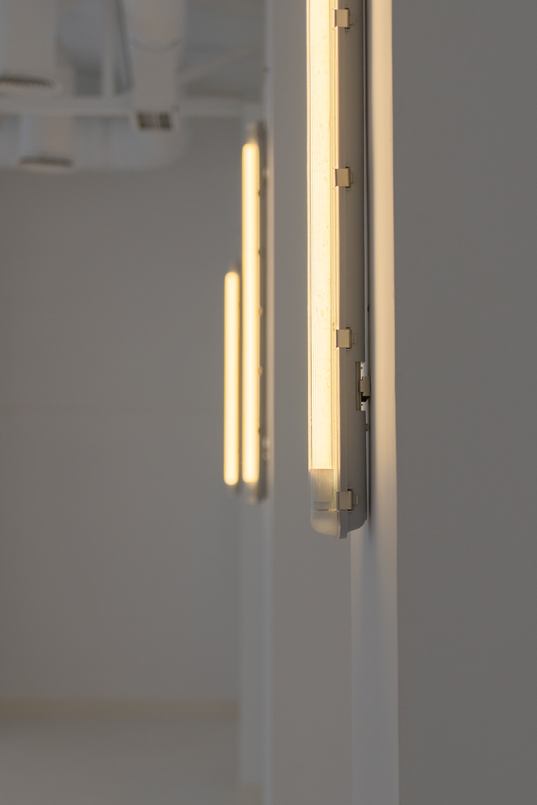 Close-up of a wall-mounted LED light fixture with a minimalist design, illuminating a small portion of the wall beneath it.
