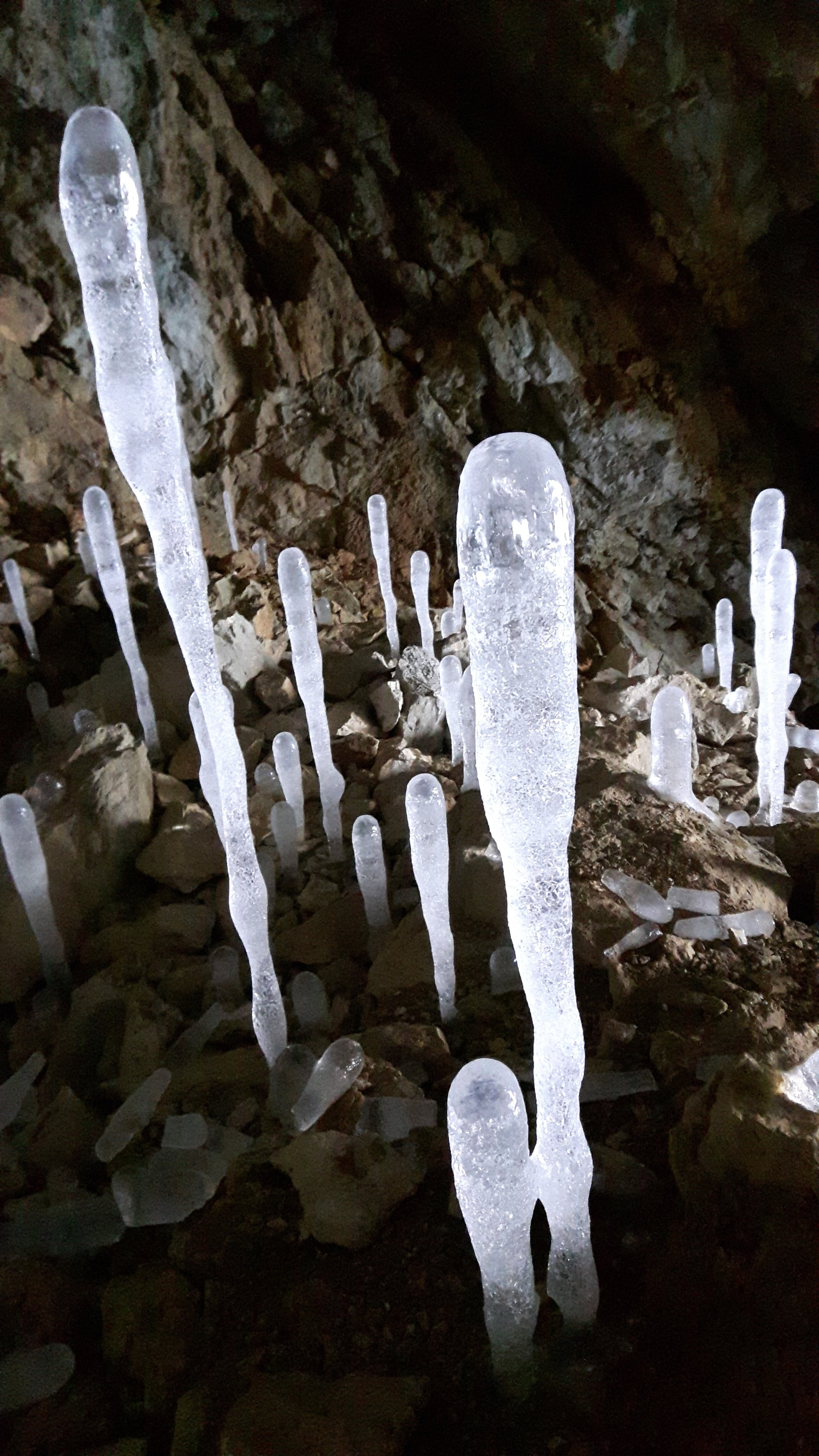 Ice stalagmites inside a dark cave formation.