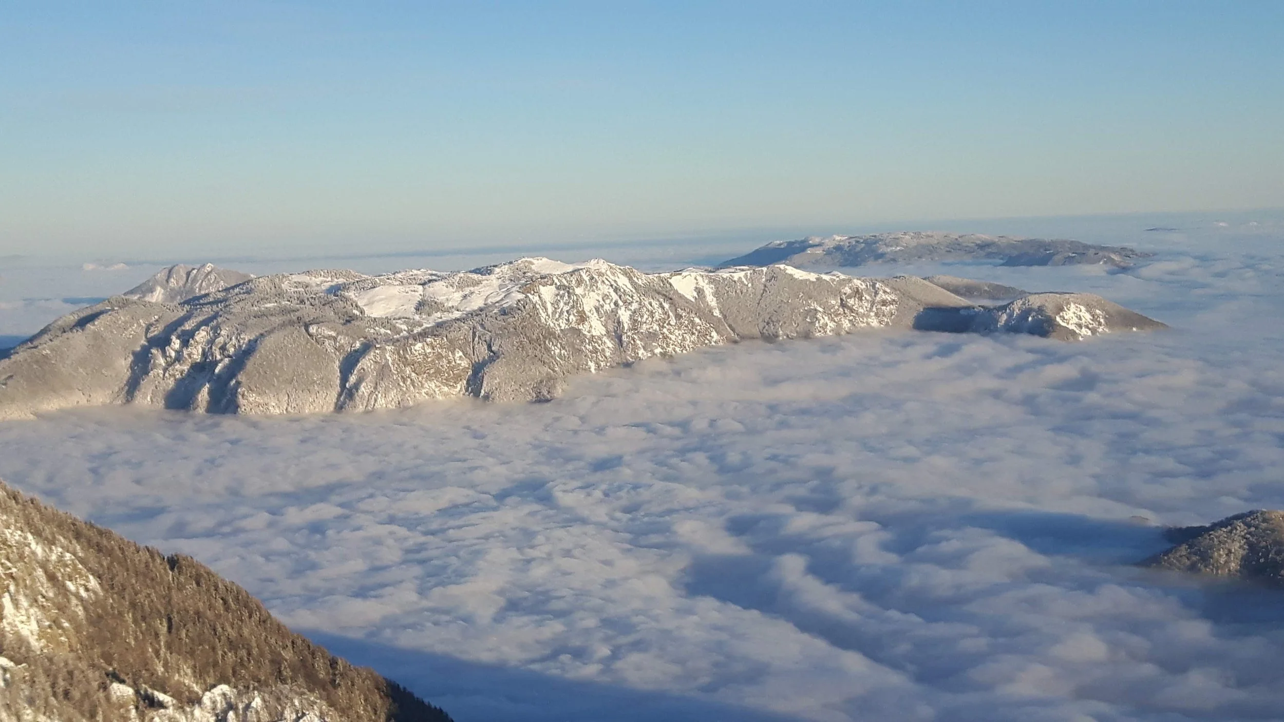 Snow-covered mountain range above a sea of clouds on a clear day.