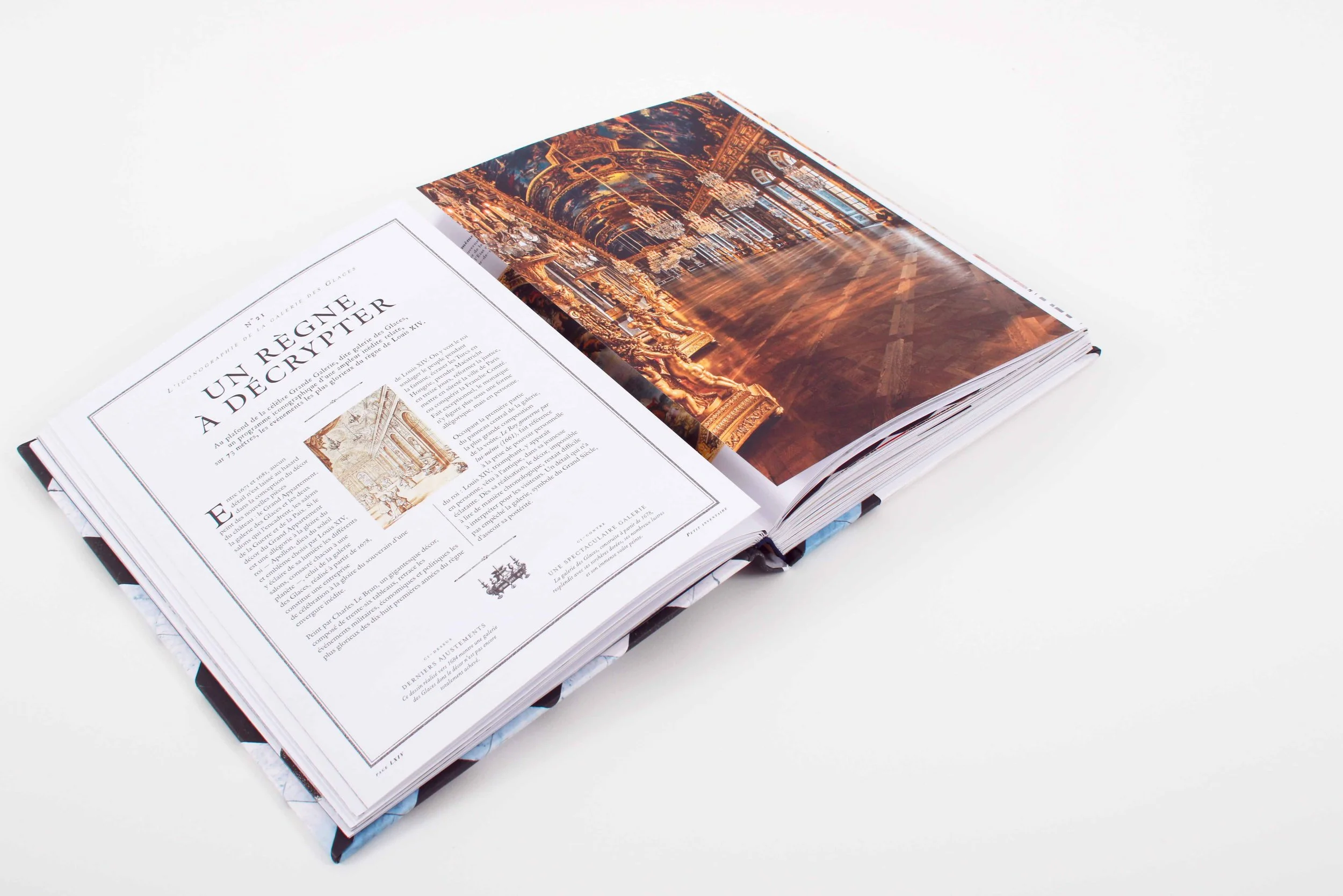 Un livre ouvert sur une table blanche decoré avec des images de l'intérieur de la cathédrale Notre-Dame de Paris, avec une page contenant un texte en français et une image miniature de la cathédrale