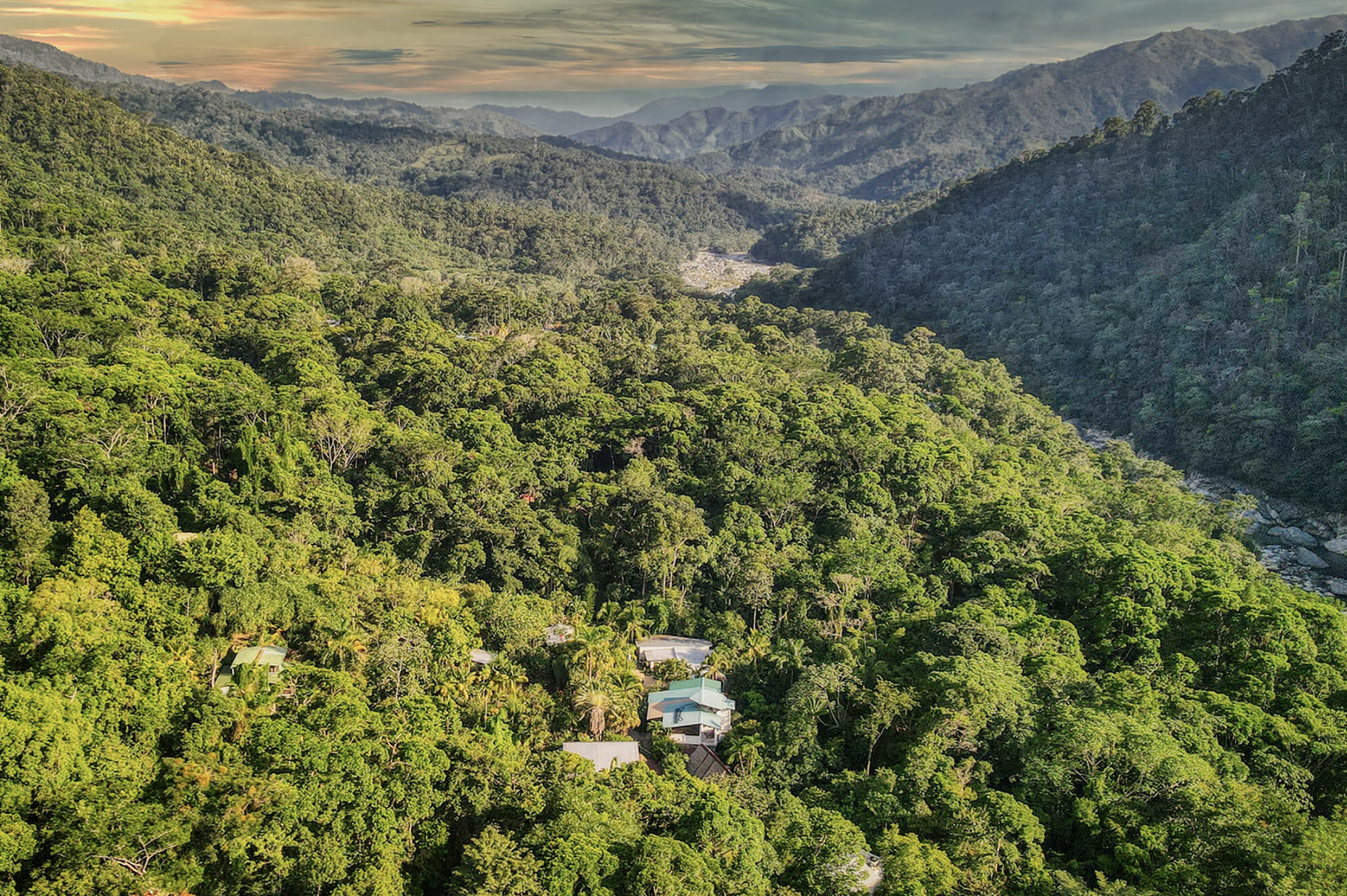 Solstice Rising Co jungle retreat site at Omega Lodge, seen from above with forested mountains and the Cangrejal River below