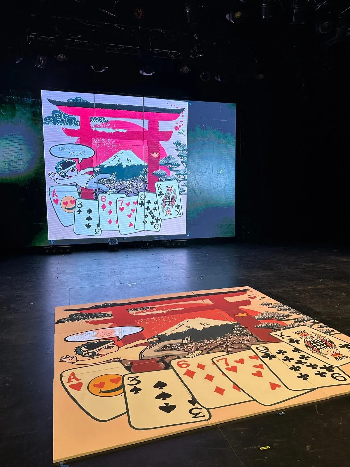 Dibujo para ilusión Jorge Blass con ilustración con elementos japoneses torii rojo, con cartas de juego en primer plano, incluyendo un as de corazones, un 3 de espadas, un 6 de diamantes, un 7 de corazones, un rey de tréboles y una reina en el fondo.