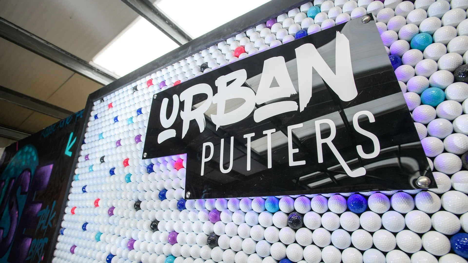 Real life image of the Urab Putters backlit sign and golf ball wall - all designed and directed by Rogue State