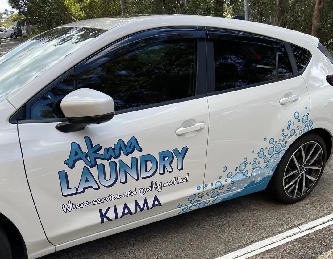 White car with lettering for Akuna Laundry and the tagline "Where service and quality matter!". 