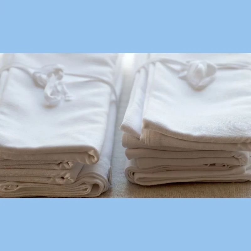 Two neatly folded packs of white linen on a flat surface.