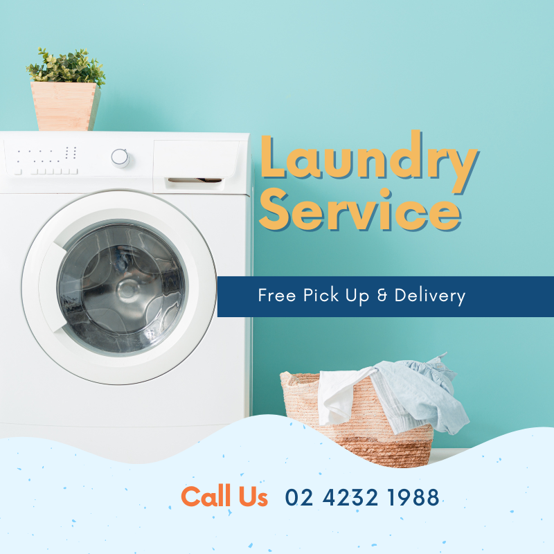 A front-loading washing machine next to a basket of laundry with folded and unfolded clothes, with a small potted plant on top of the machine, against a light blue wall.