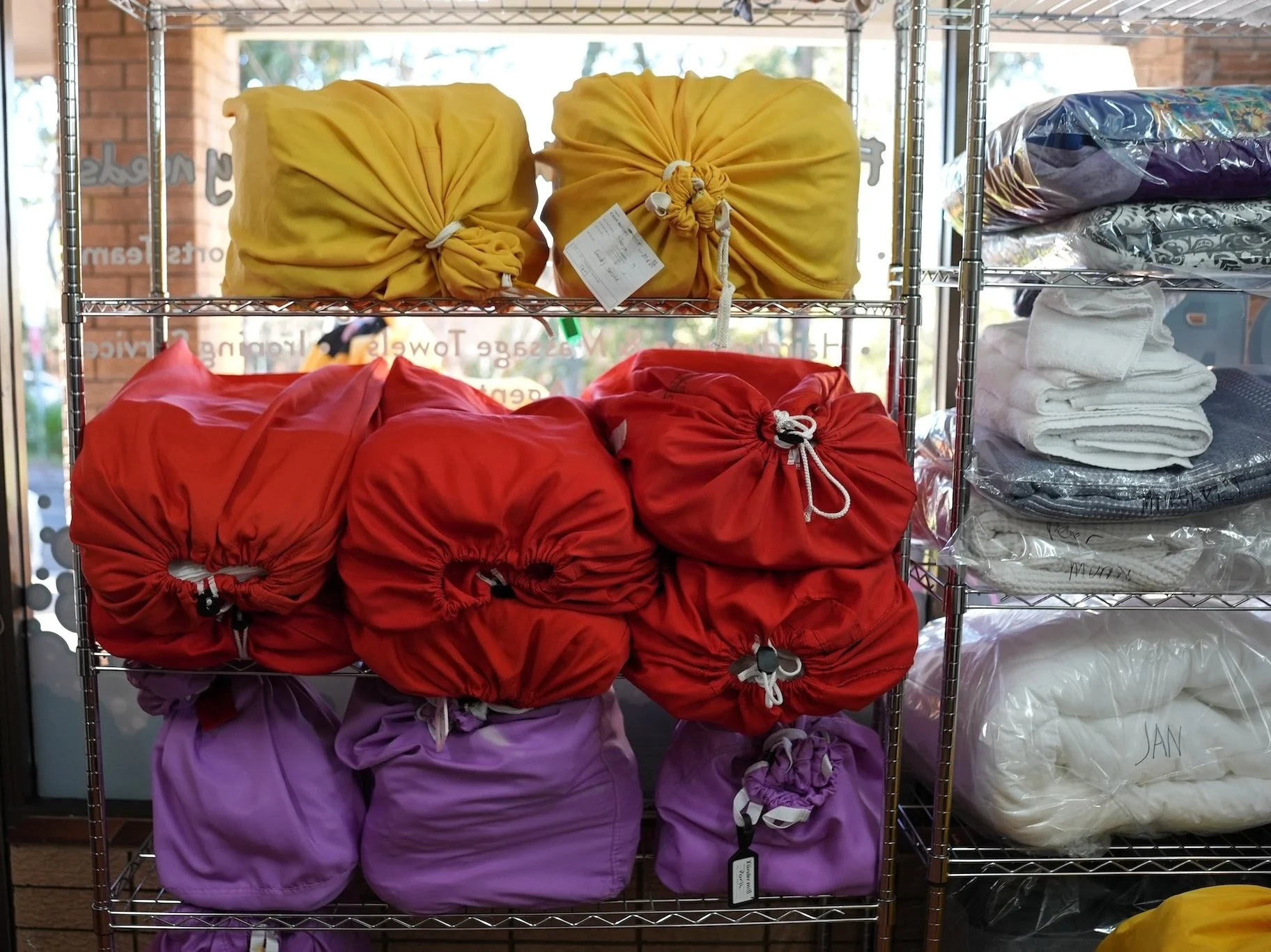 coloured laundry bags on stainless steel shelves.