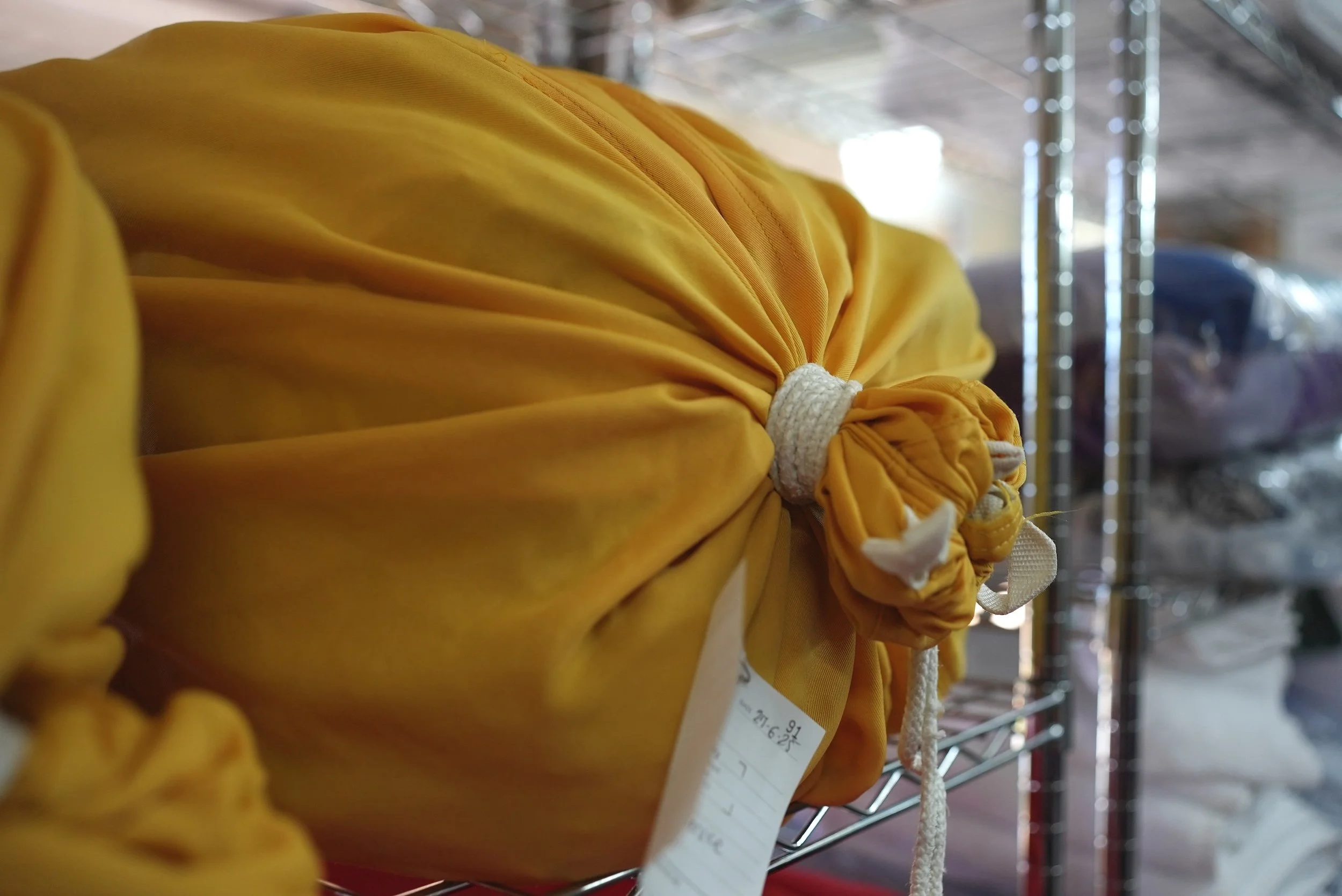 Yellow fabric bags of freshly laundered items on a metal shelf in Akuna Laundry.