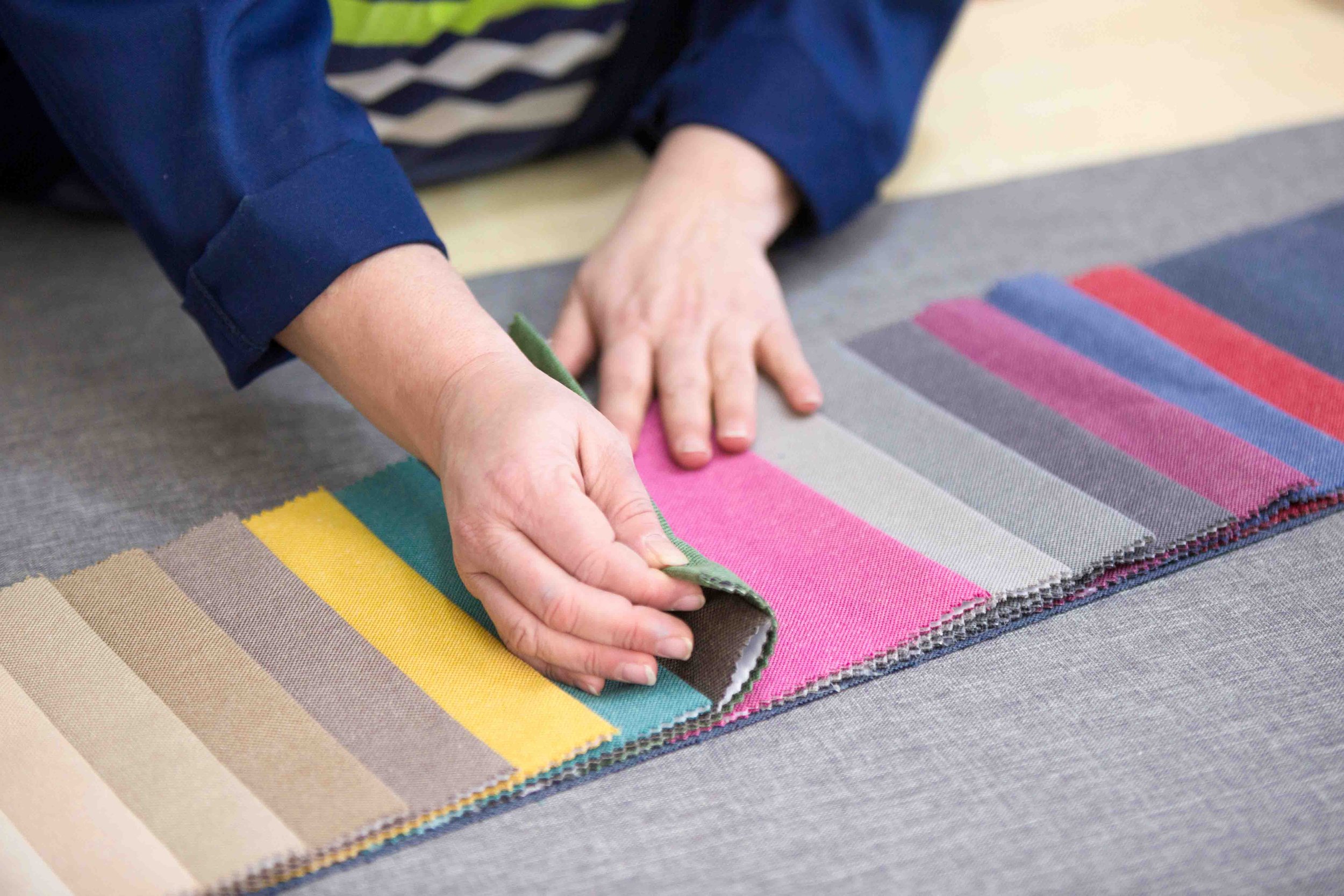 A close up of a person selecting materials from a sample book, paying attention to colour, texture and quality of the materials