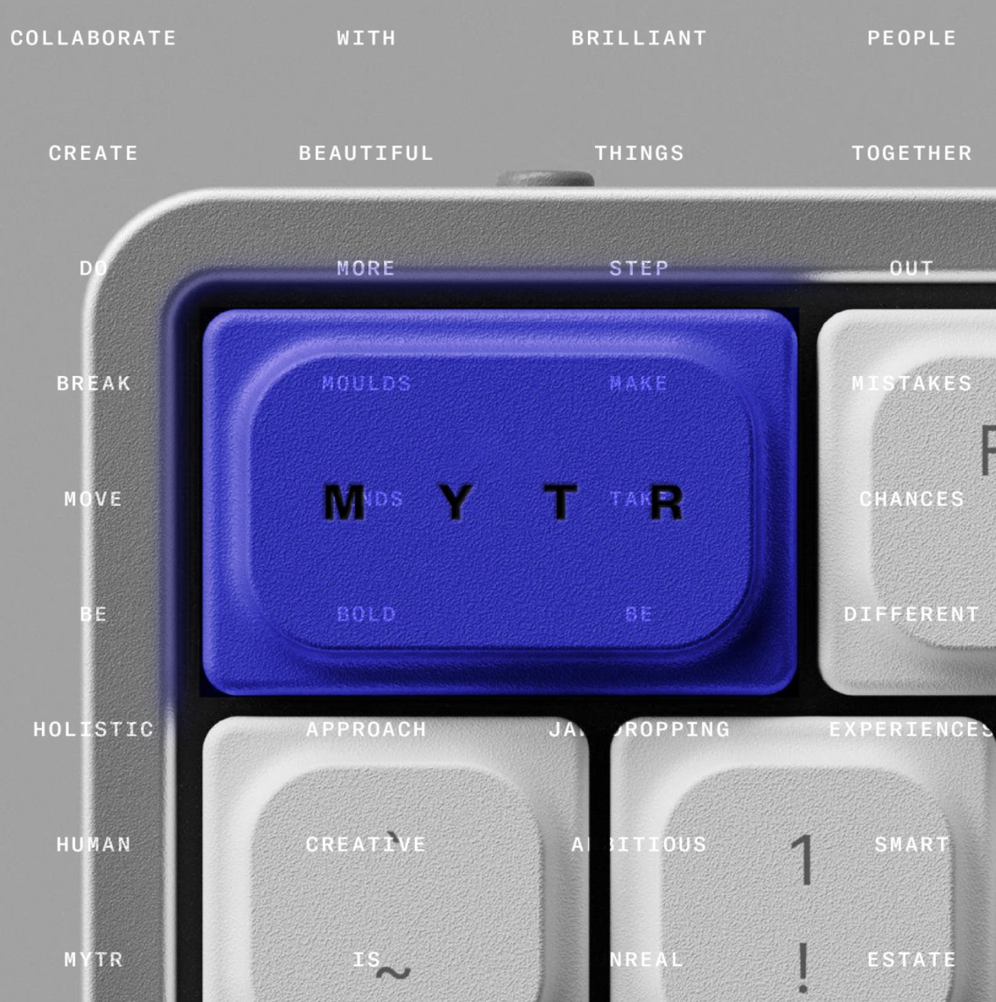 A close-up view of a digital interface with a blue button in the center displaying the letters M, Y, T, R, and surrounding words encouraging creativity and collaboration, such as 'collaborate,' 'create,' 'beautiful,' 'think,' and 'together' on a gray background.