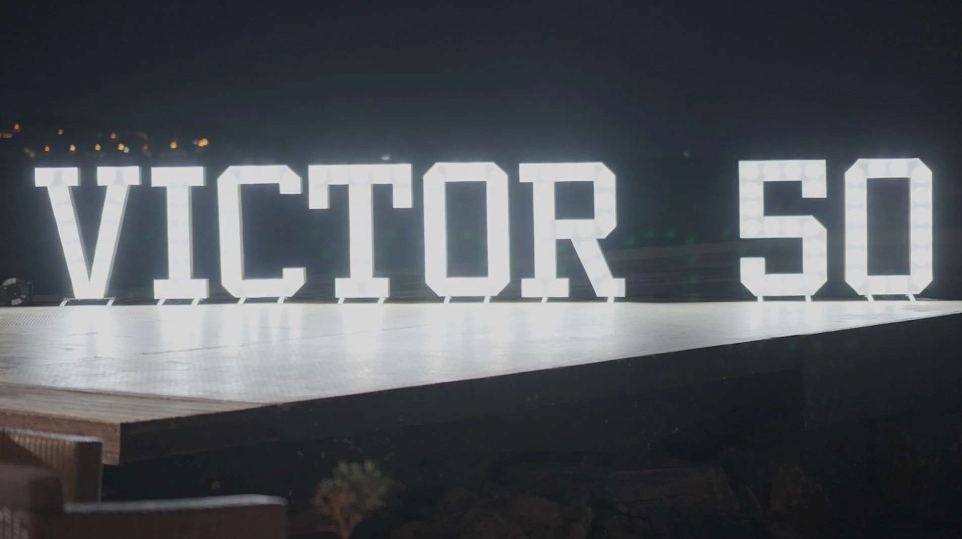 Grand panneau lumineux avec le texte 'VICTOR 50' en lettres majuscules, situé en extérieur la nuit.