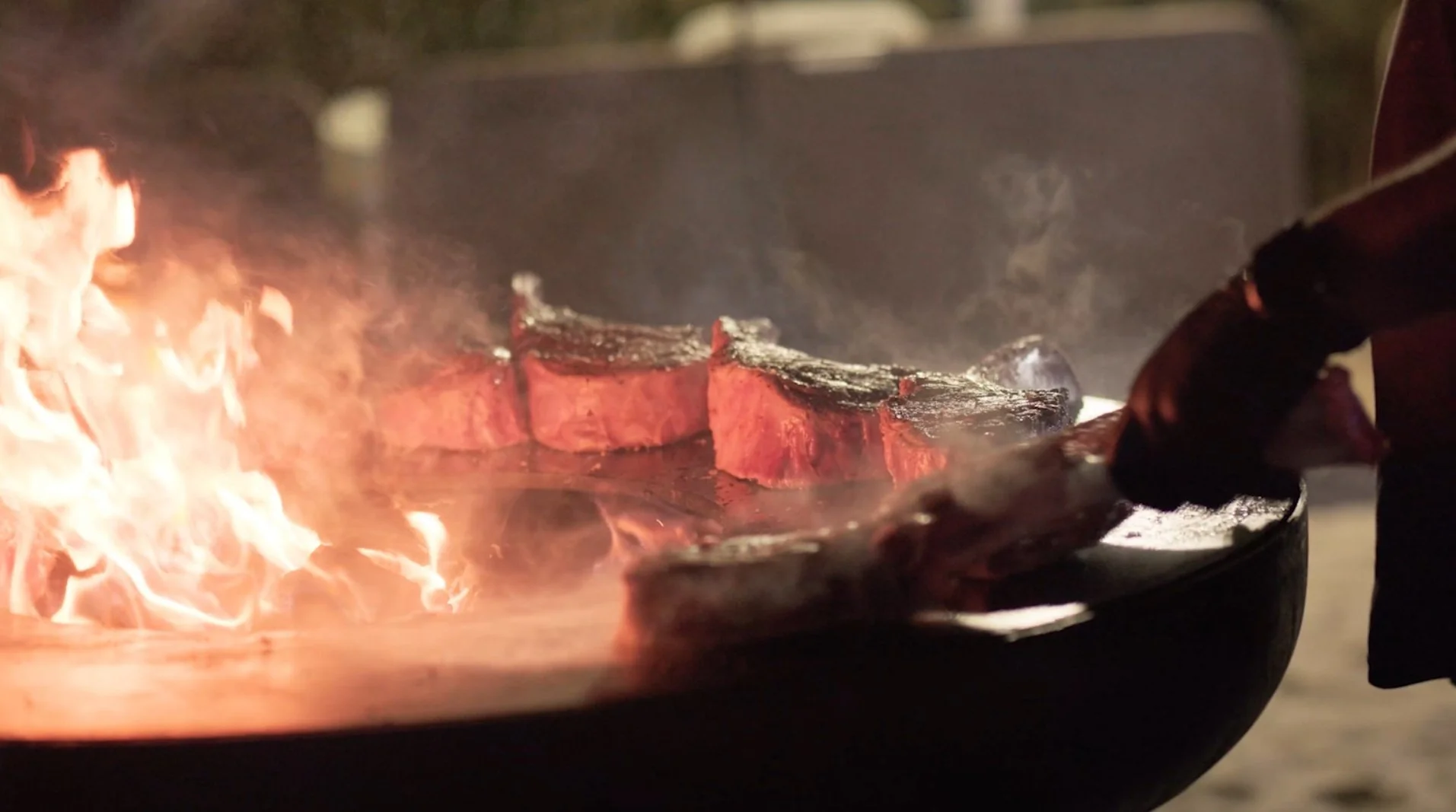 Des steaks en train de cuire sur un barbecue avec des flammes