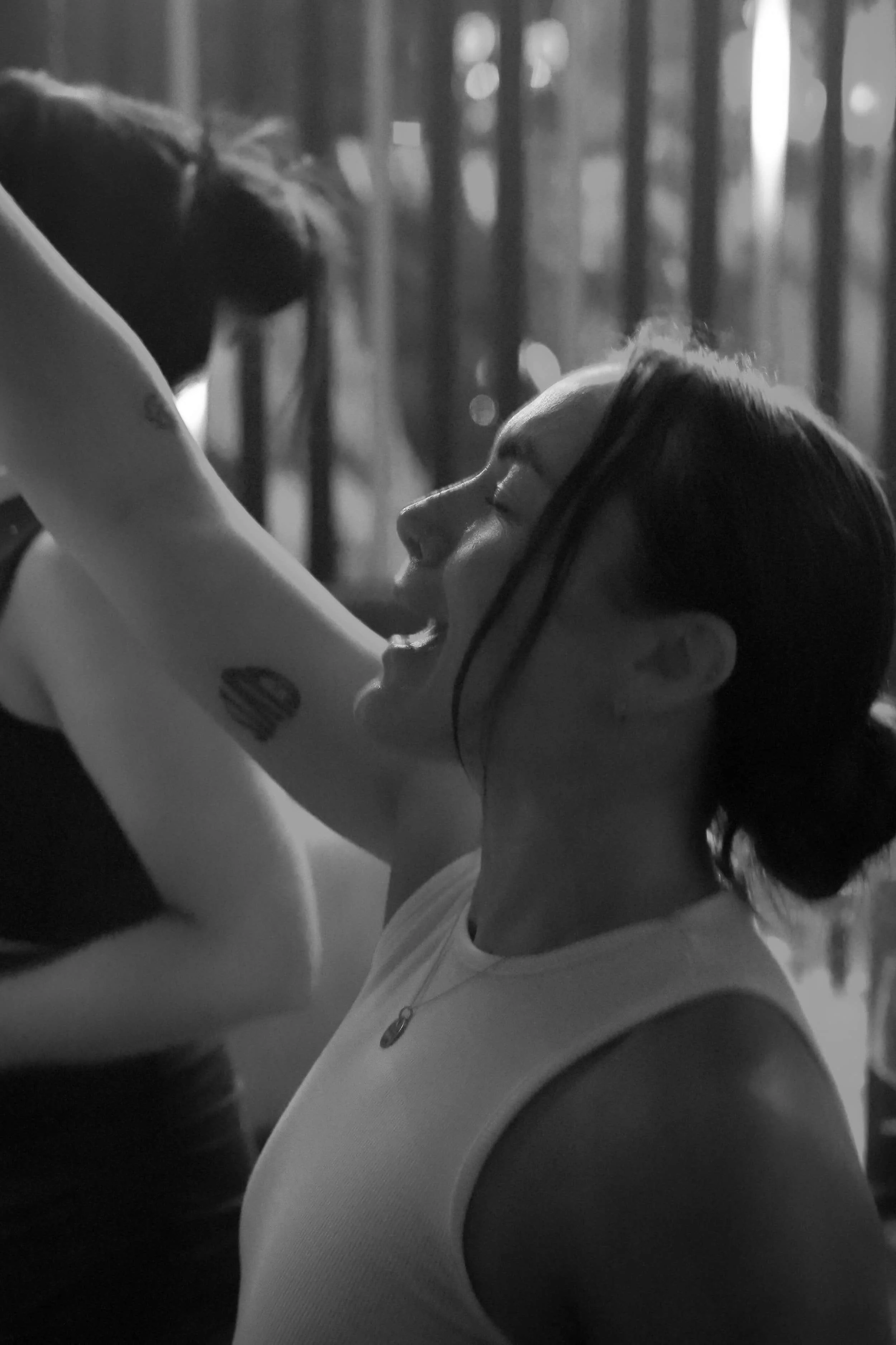 Deux femmes souriantes en gros plan, dans une scène en noir et blanc, l'une d'elles porte un jean et une chaîne