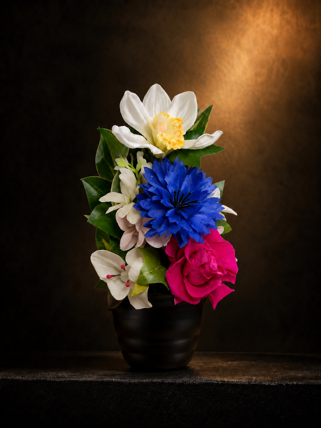 イノリユイの仏花「souka（想花）」を左斜め45度から撮影した商品画像。白・青・濃いピンクの花々を黒い花器に上品に合わせた、マサコモデストの高級感あるアーティフィシャルフラワーの供養花。
