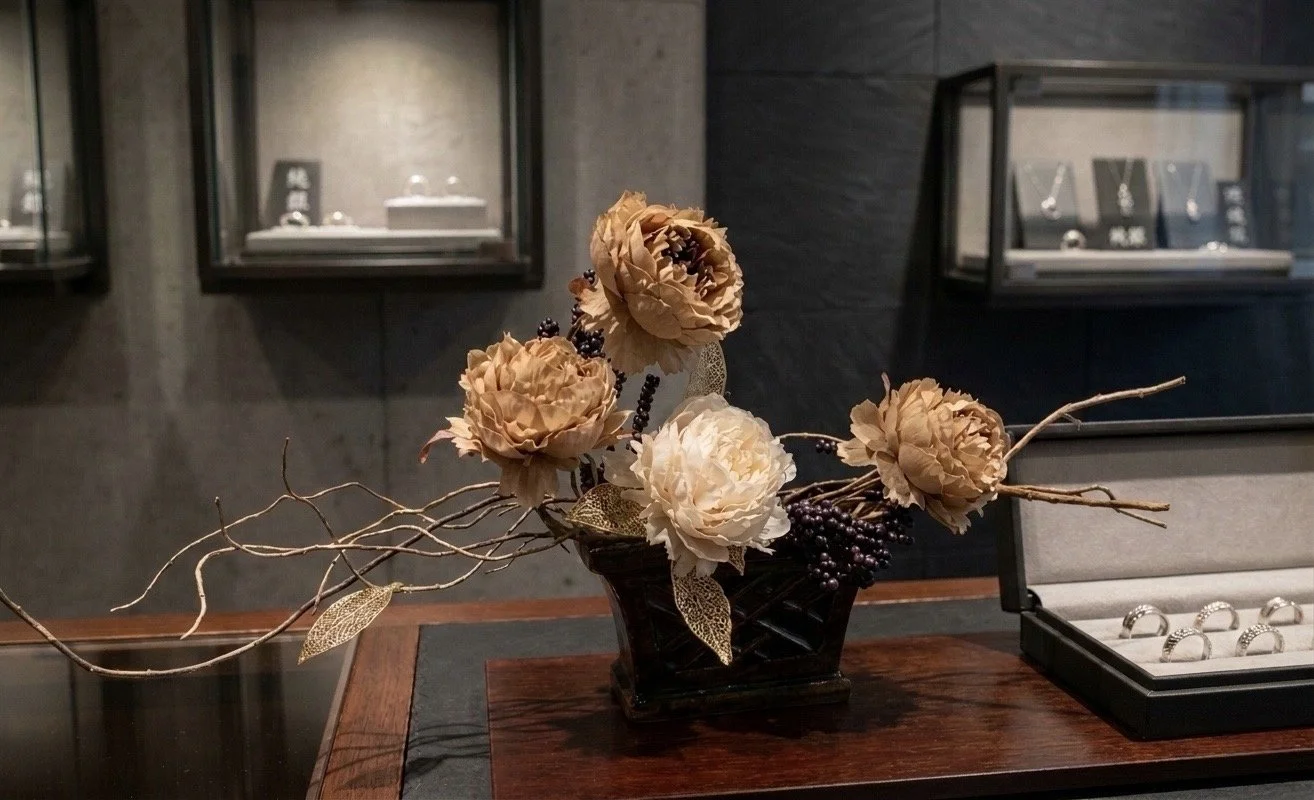 高級宝石店のショーケースに飾られた、気品漂うレンタルフラワーのディスプレイ