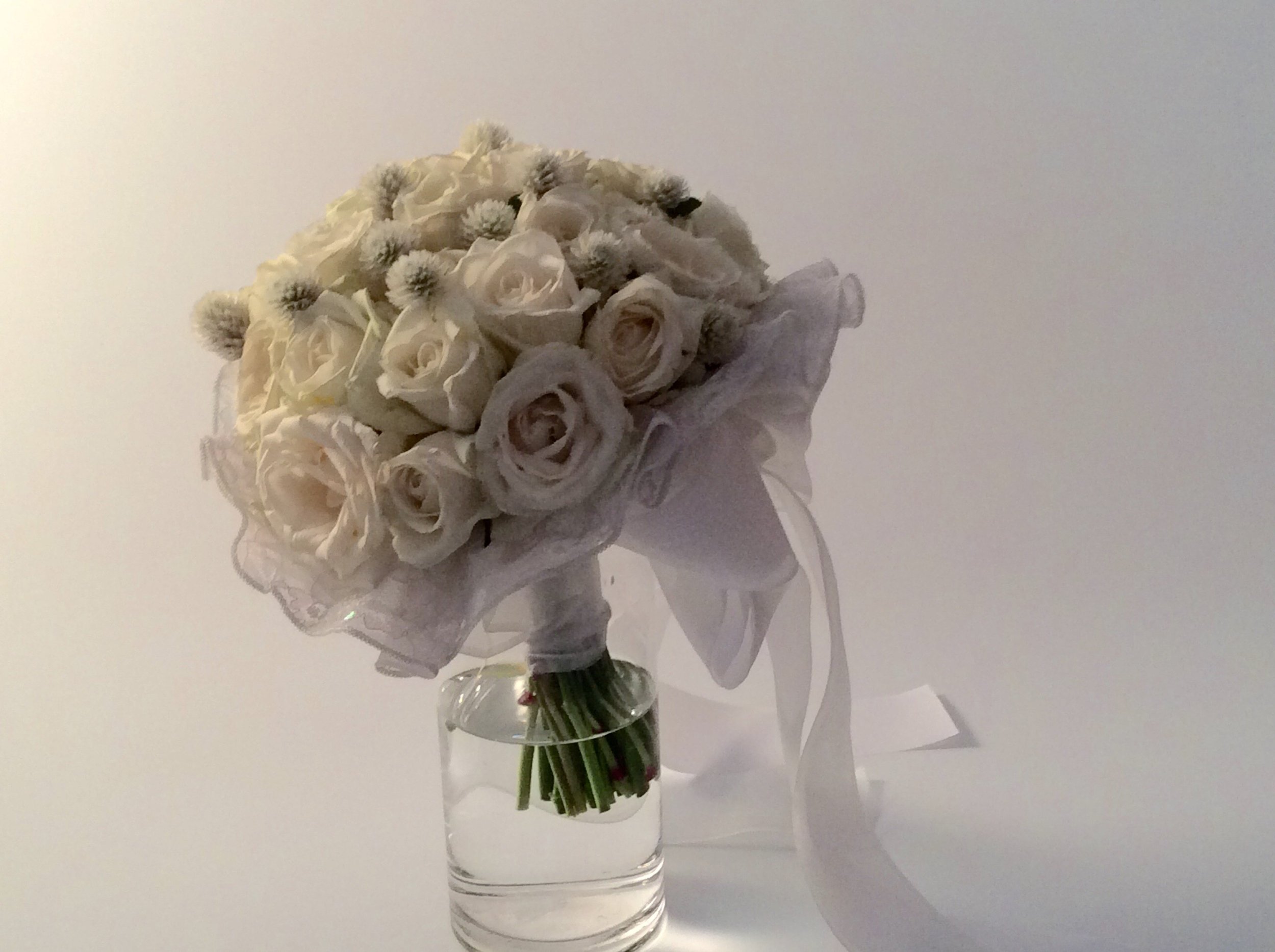 白いバラと小さな丸い花のブーケがガラスの花瓶に入っている