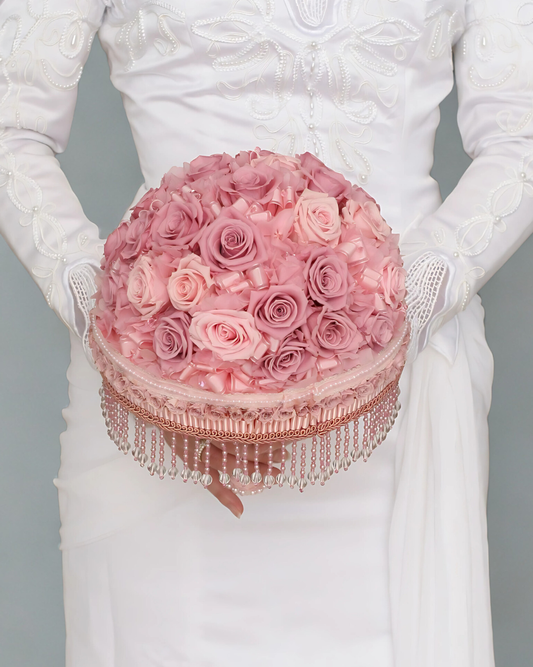 白いドレスを着た人がピンクのバラの花束を持っている