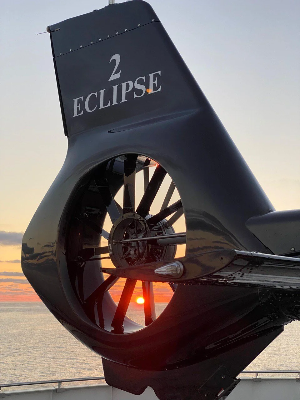Close-up of a helicopter tail rotor with the sunset in the background.