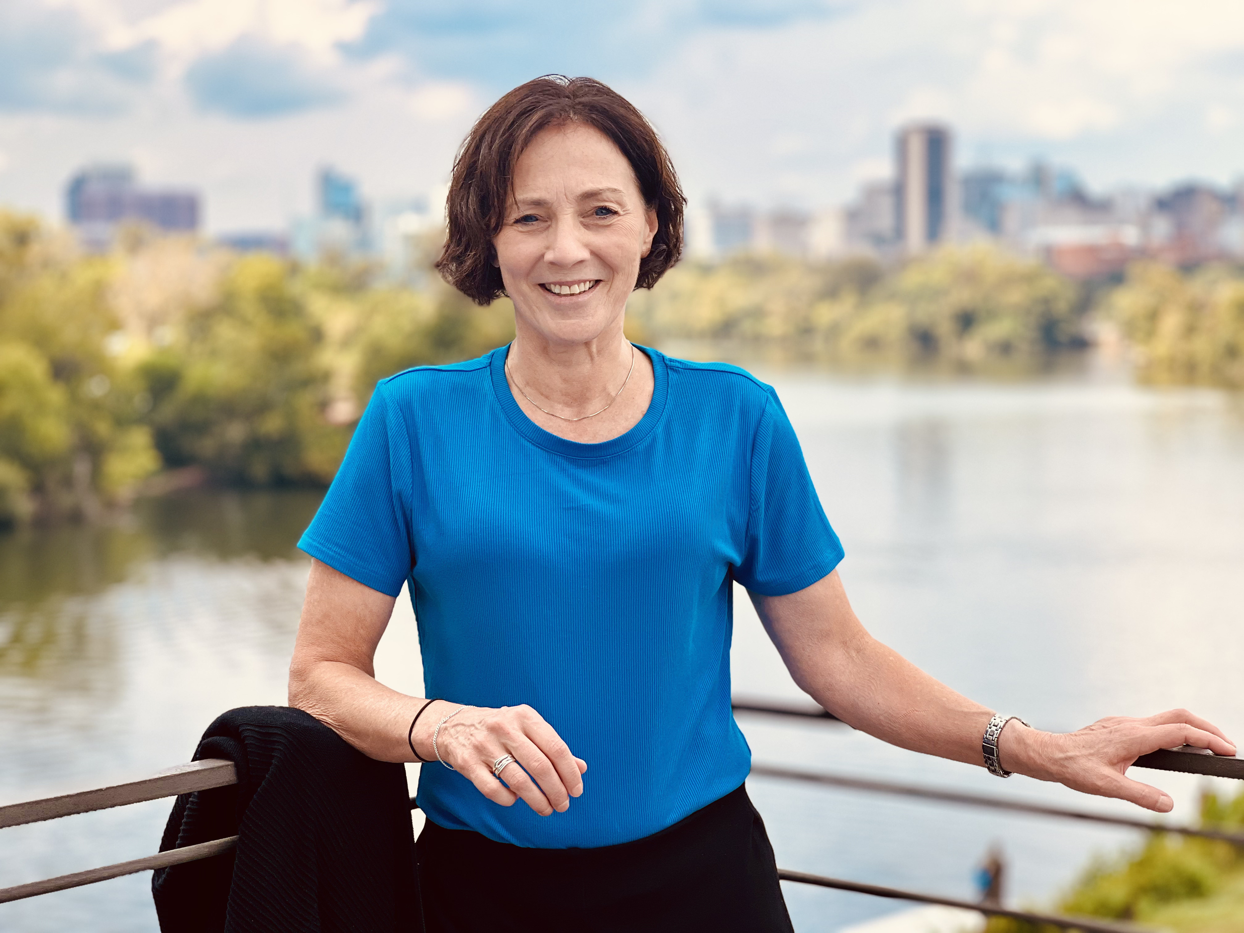 White woman standing before a riverfront view of a city