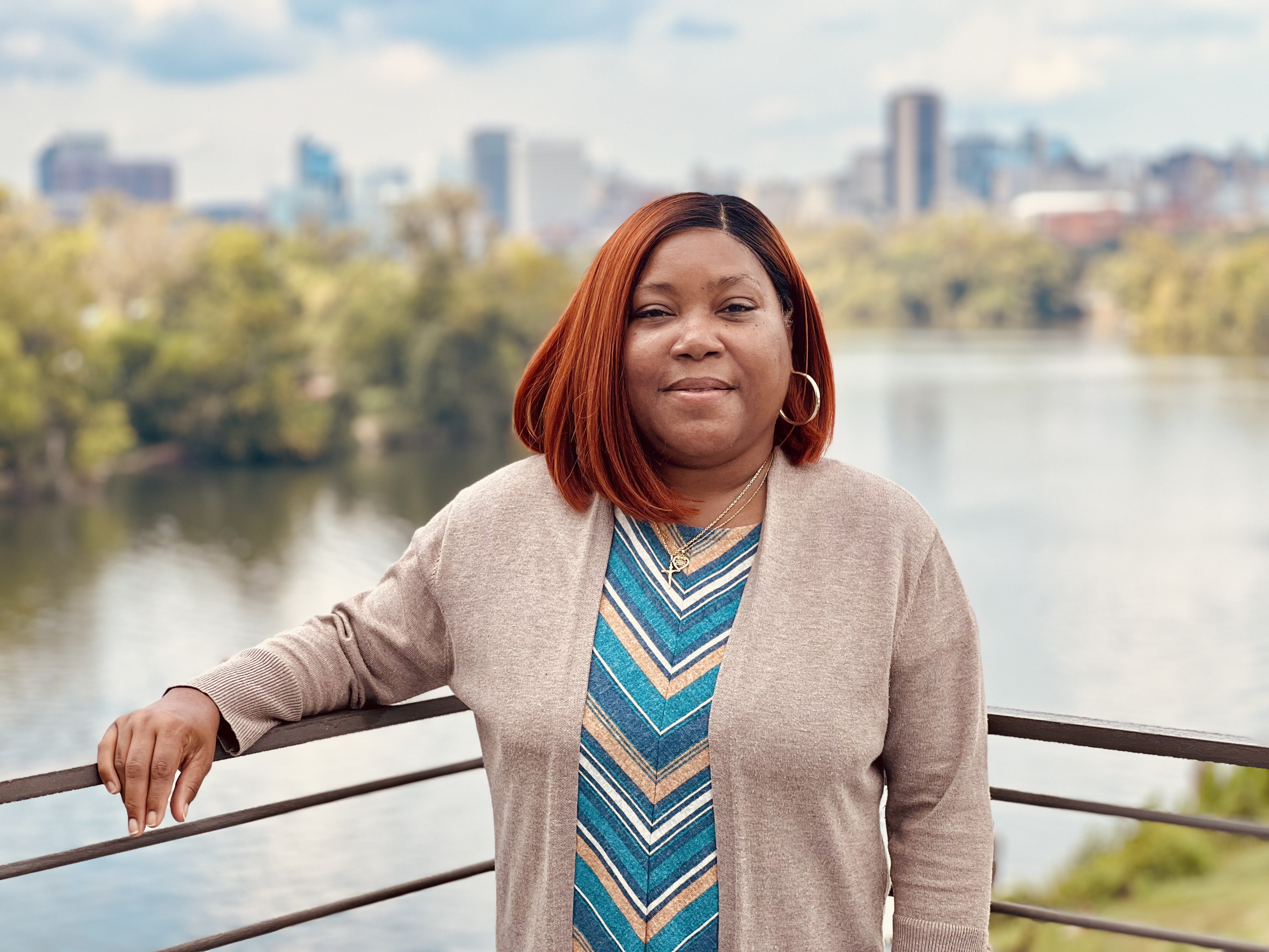 Black woman standing before a riverfront view of a city