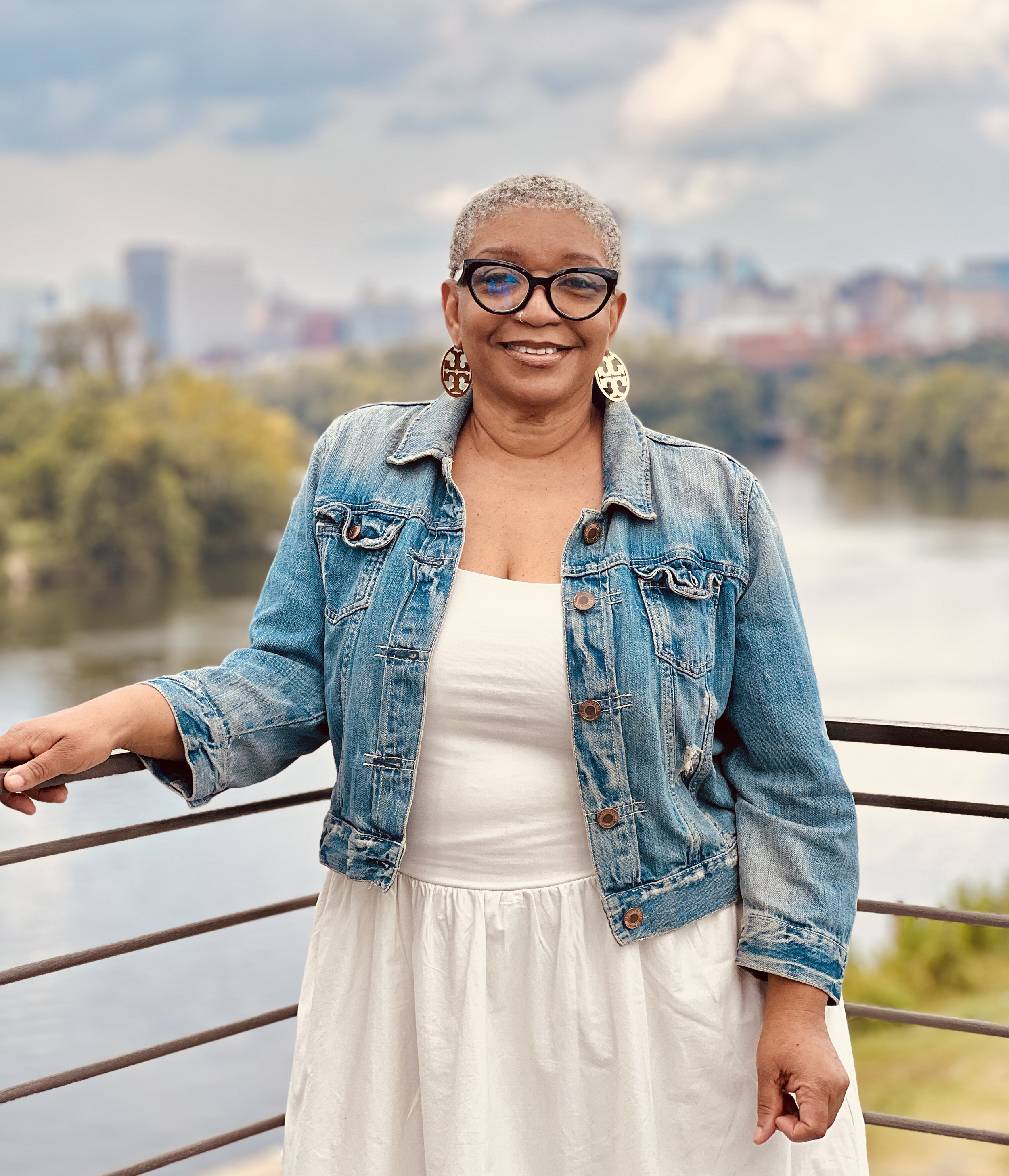 Black woman standing before a riverfront view of a city on a sunny day