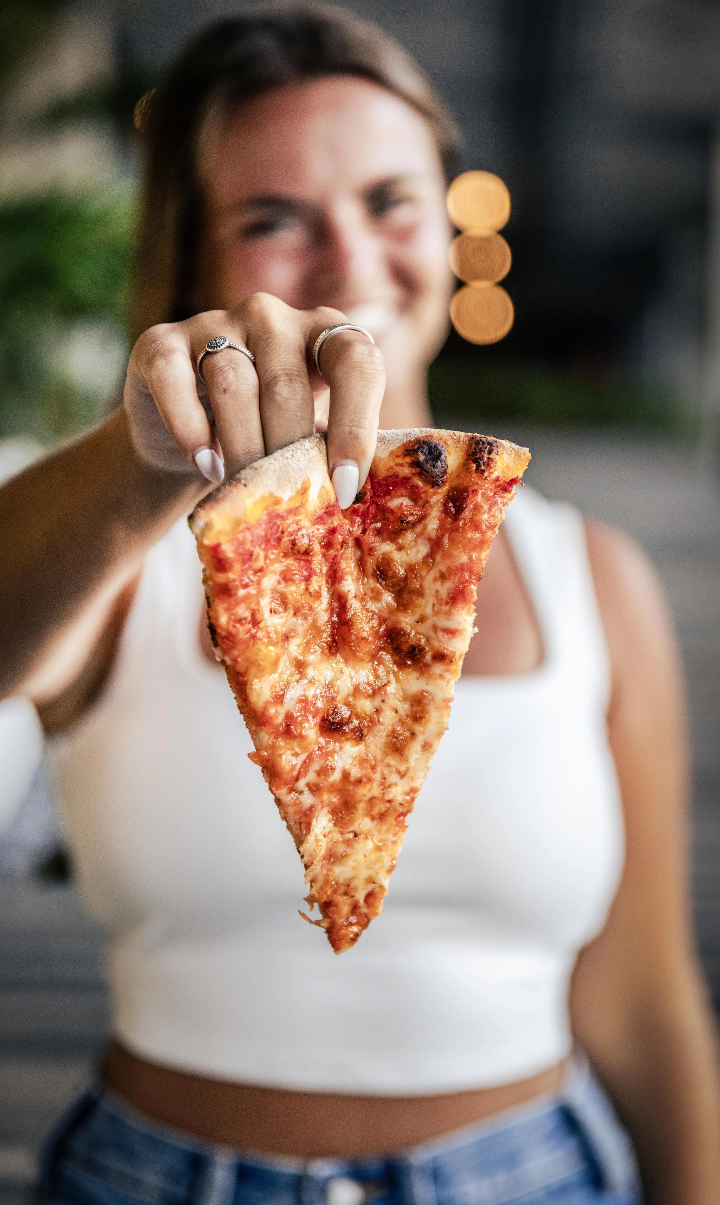 Woman holding a slice of pepperoni pizza.