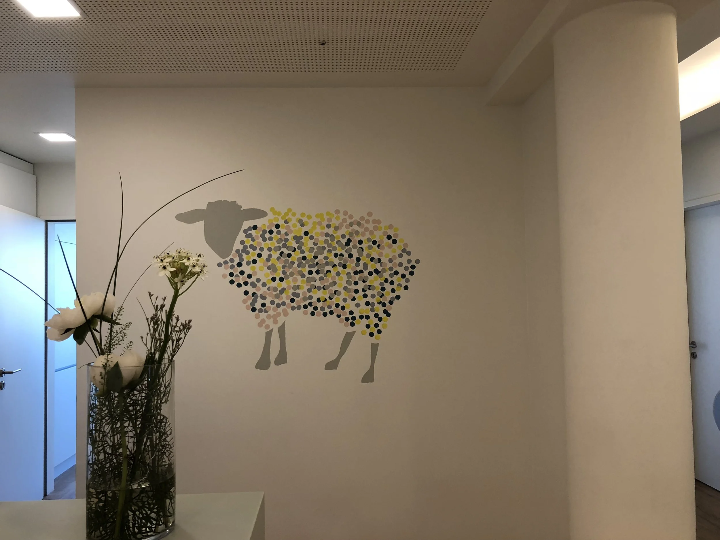 Wandbild eines Schafes mit bunten Punkten in einem Flur