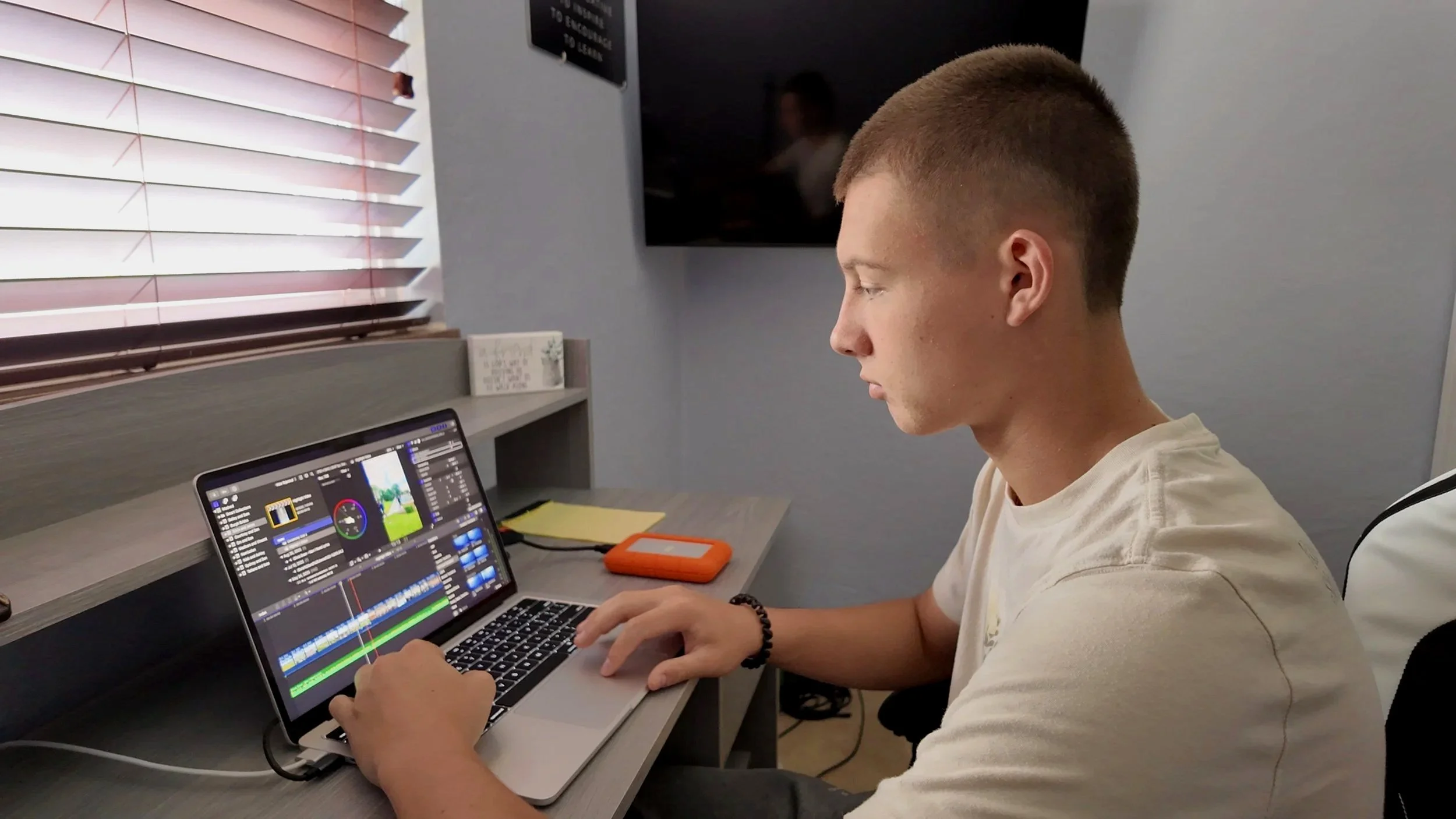 Video editor working at a desk editing footage on a laptop
