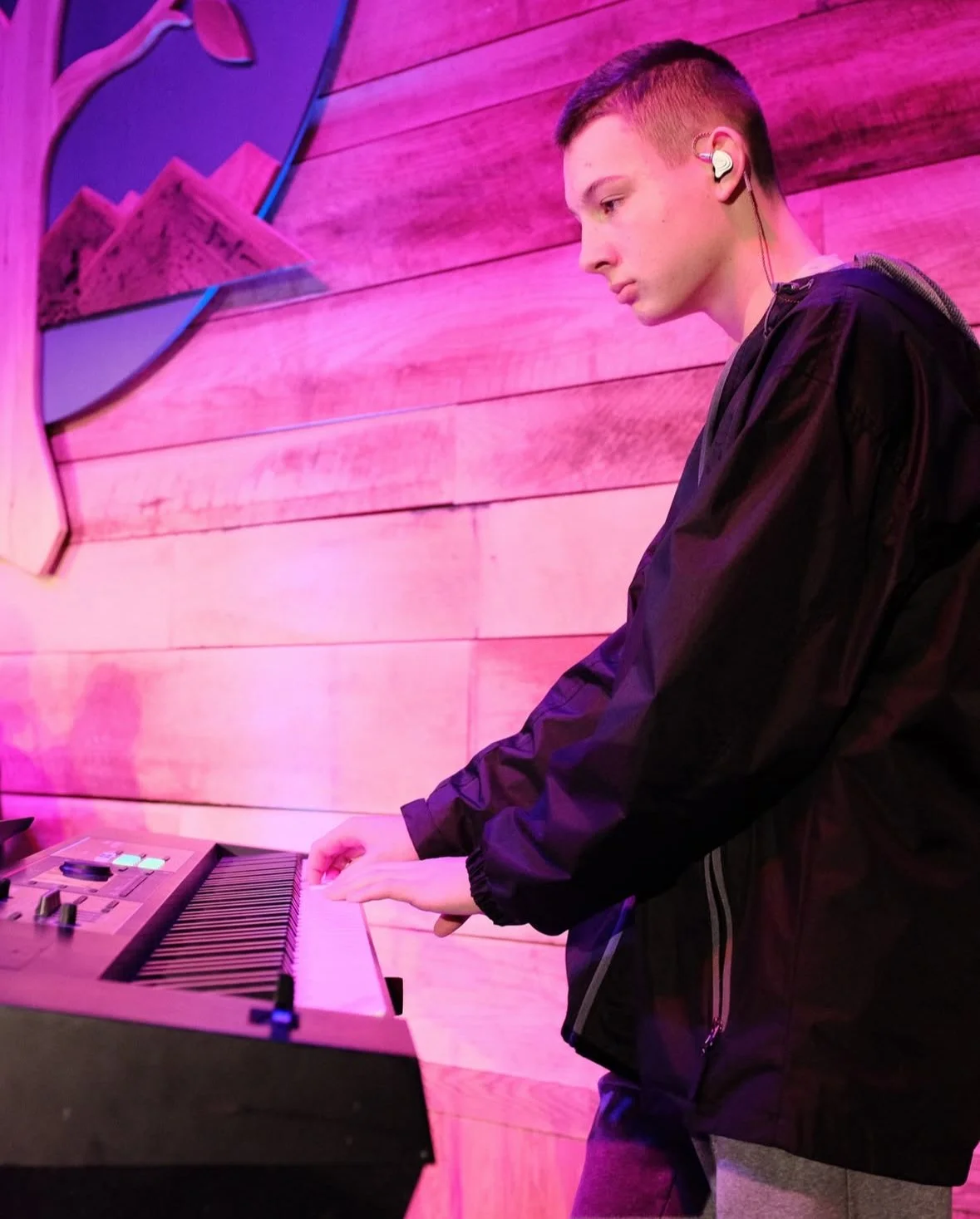 A young person with short hair playing a keyboard