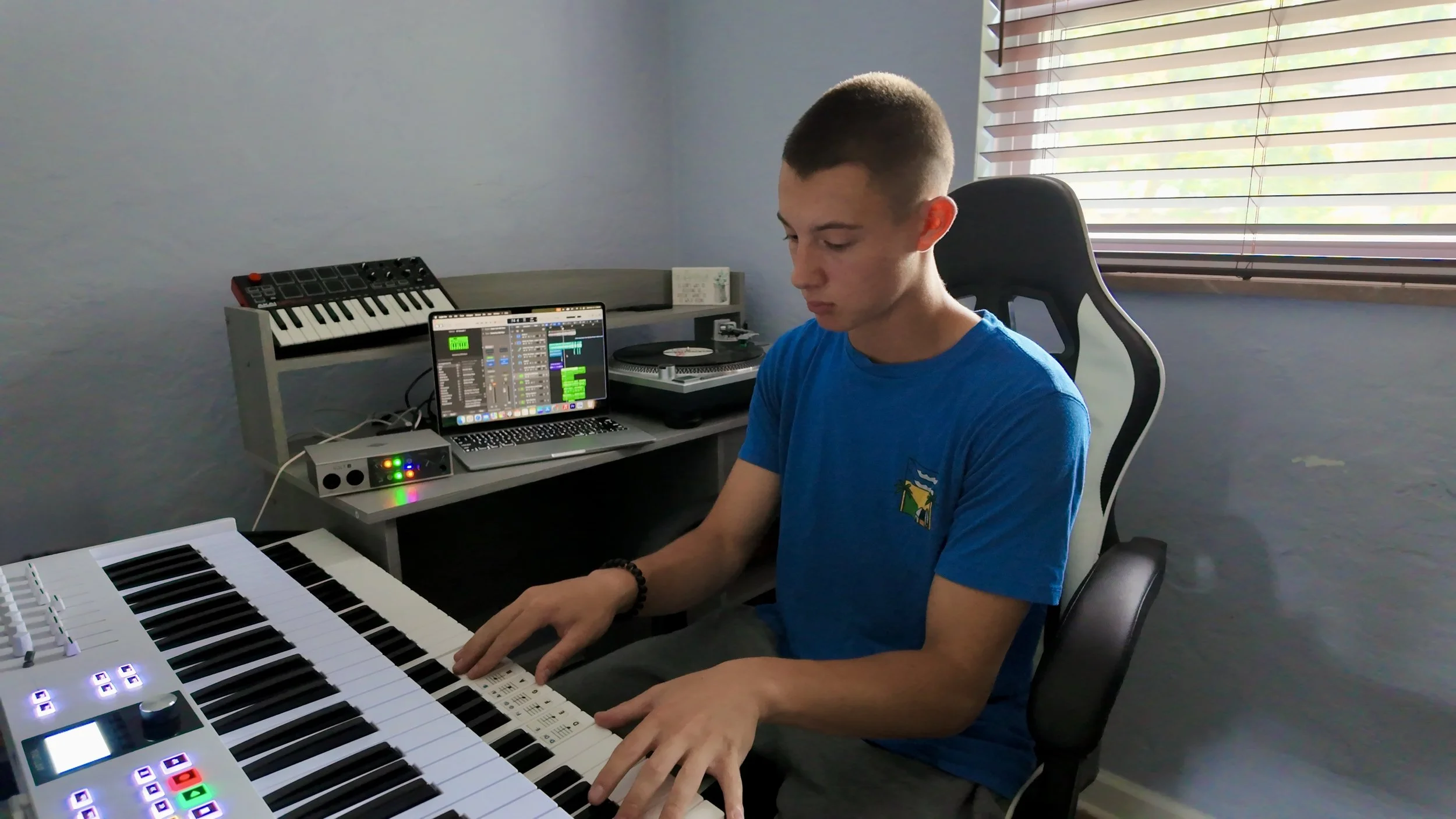 Musician playing a keyboard in a home studio setup