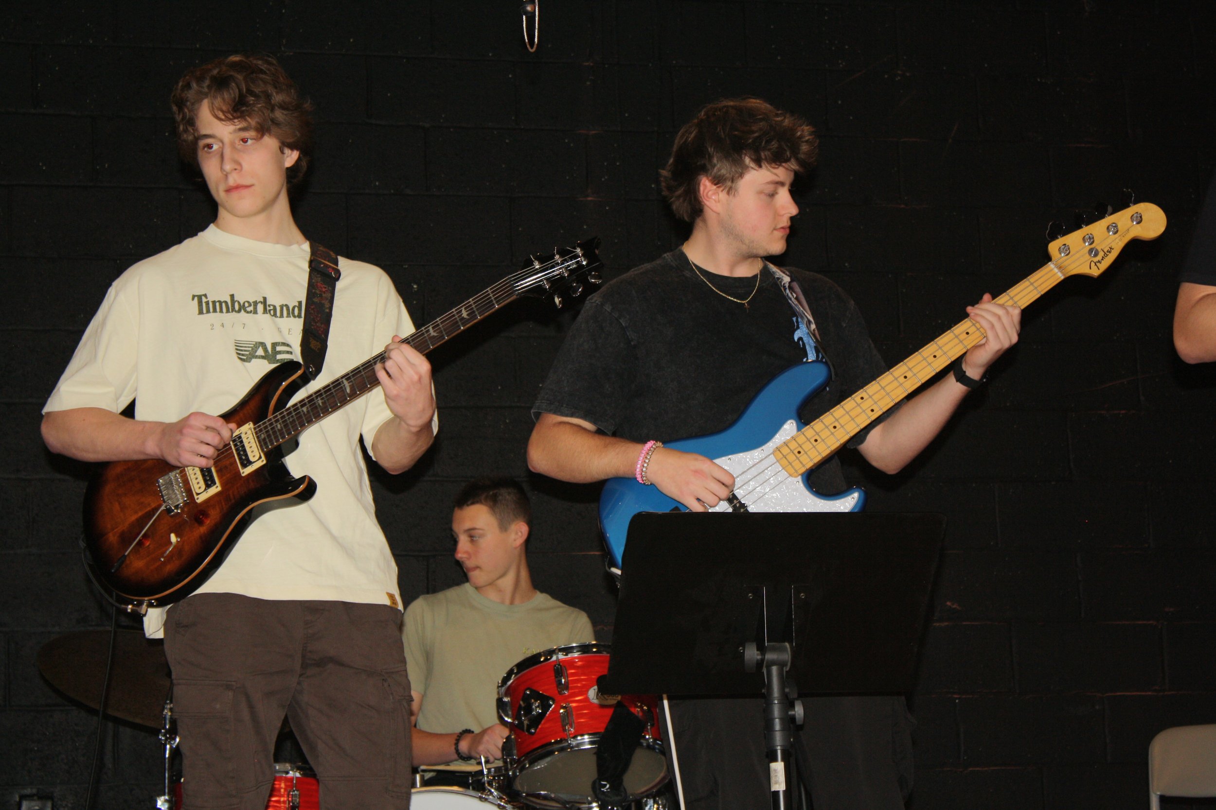 Three young men playing musical instruments on stage