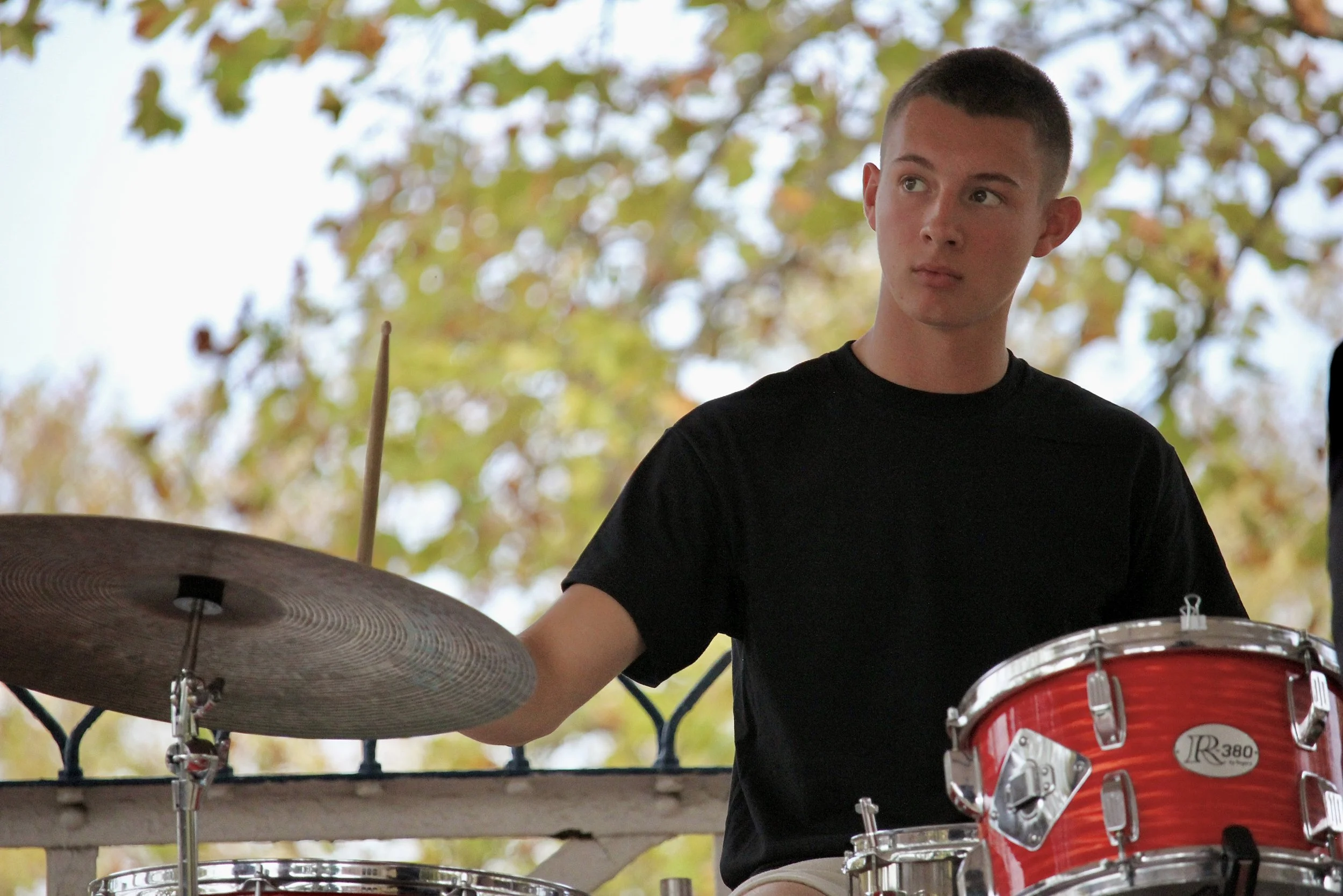 A young man playing drums outdoors