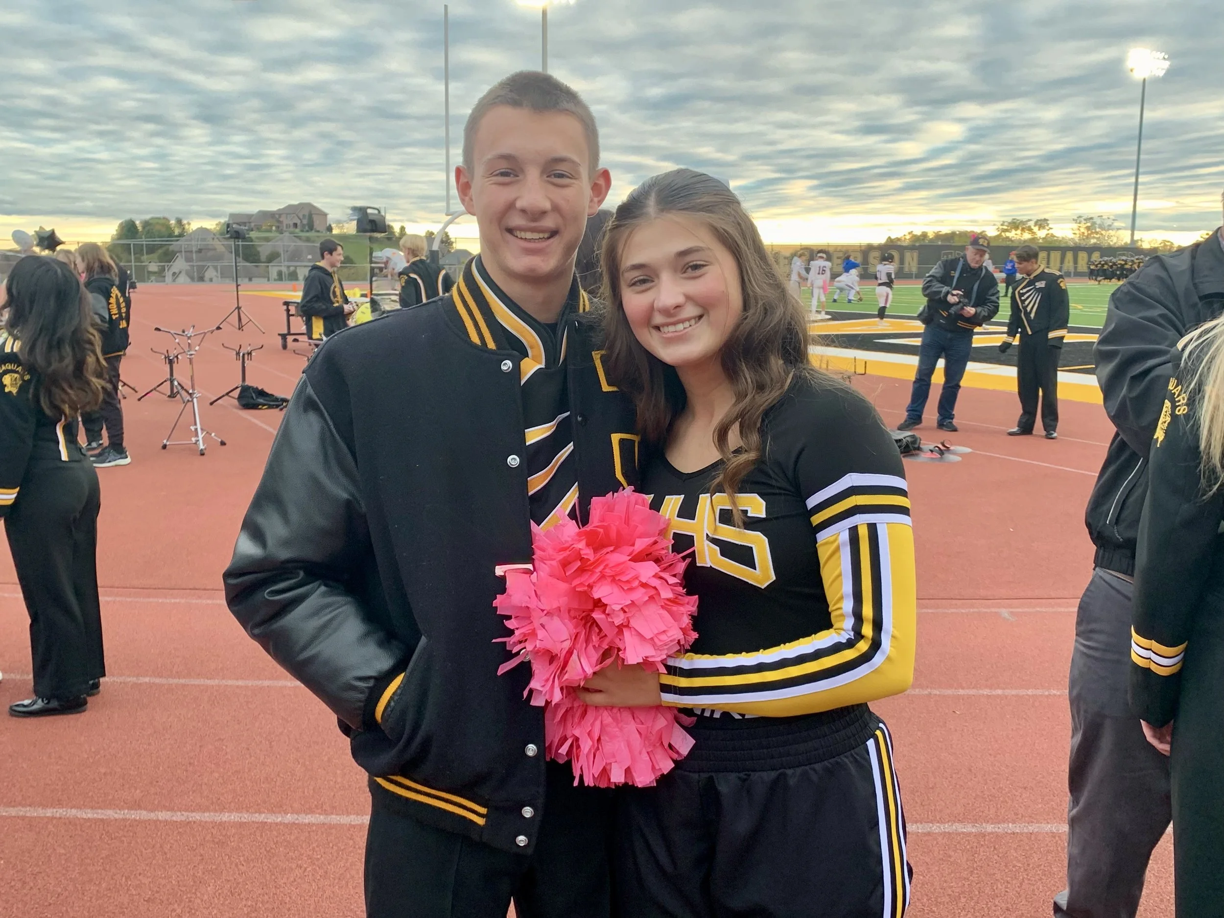 Two people posing together on a sports field during a school event