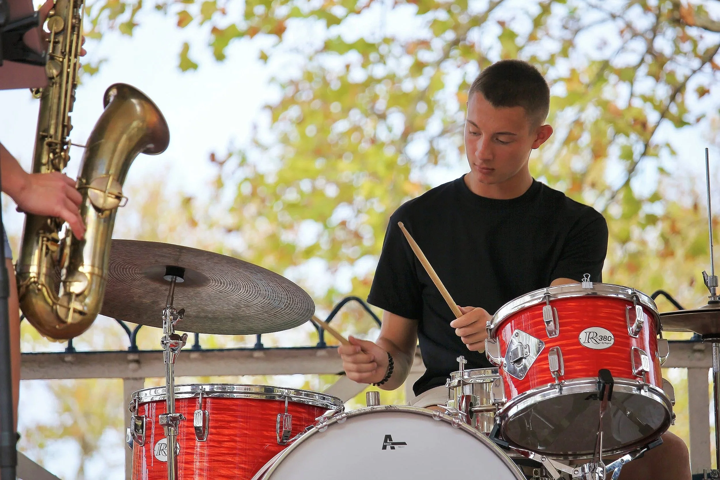 A teenage boys playing drum set outside