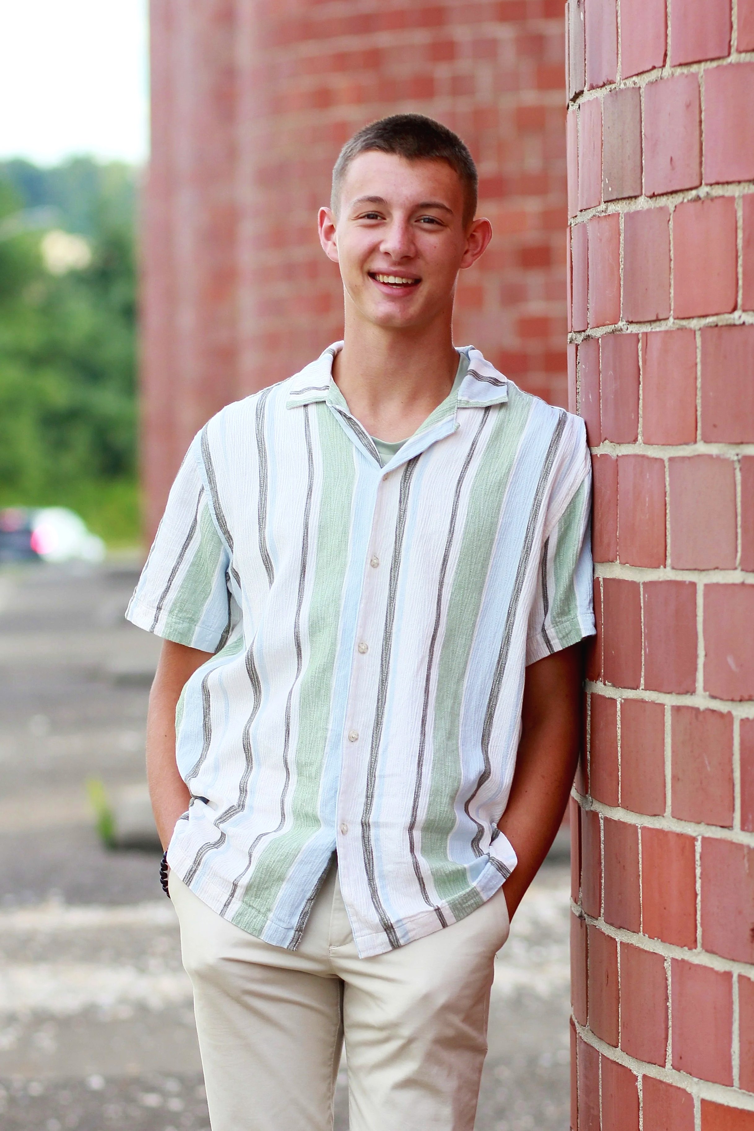 Portrait of Isaiah Vinay, video editor and musician, standing against a brick wall outdoors