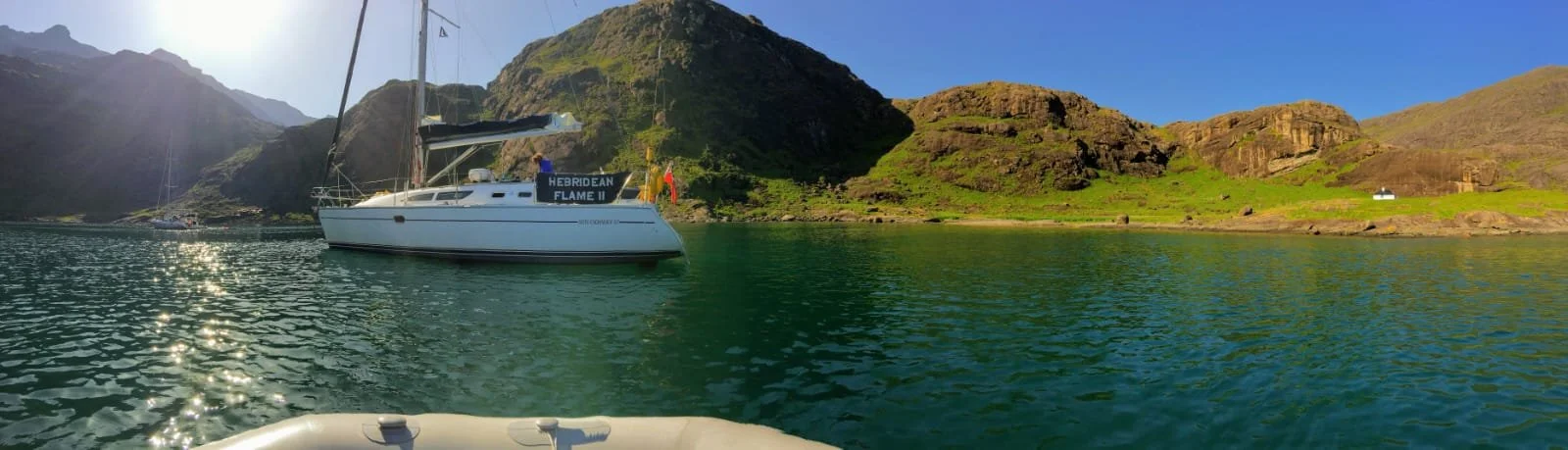 A boat floating on a calm body of water with mountainous landscape in the background under clear blue sky