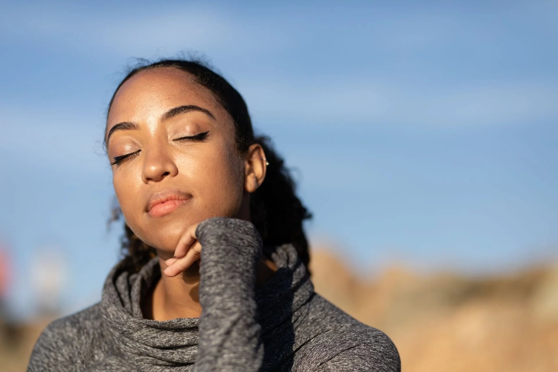 A professional woman with eyes closed exhibiting deep physiological regulation and emotional stability under the WellThera framework.