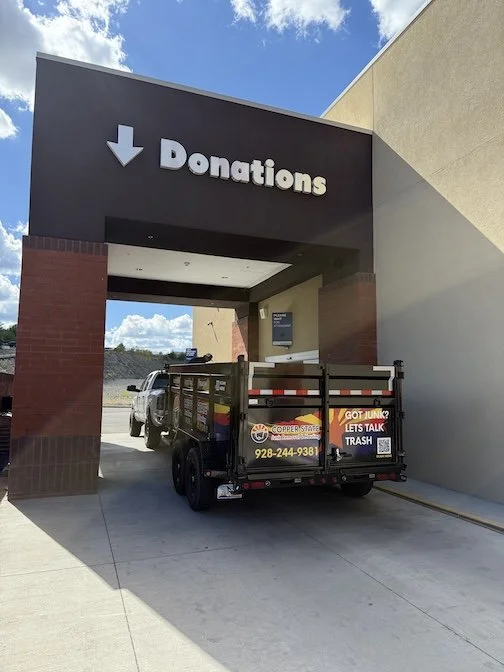 A small truck parked under an overhang with a sign that reads 'Donations' with a downward arrow.
