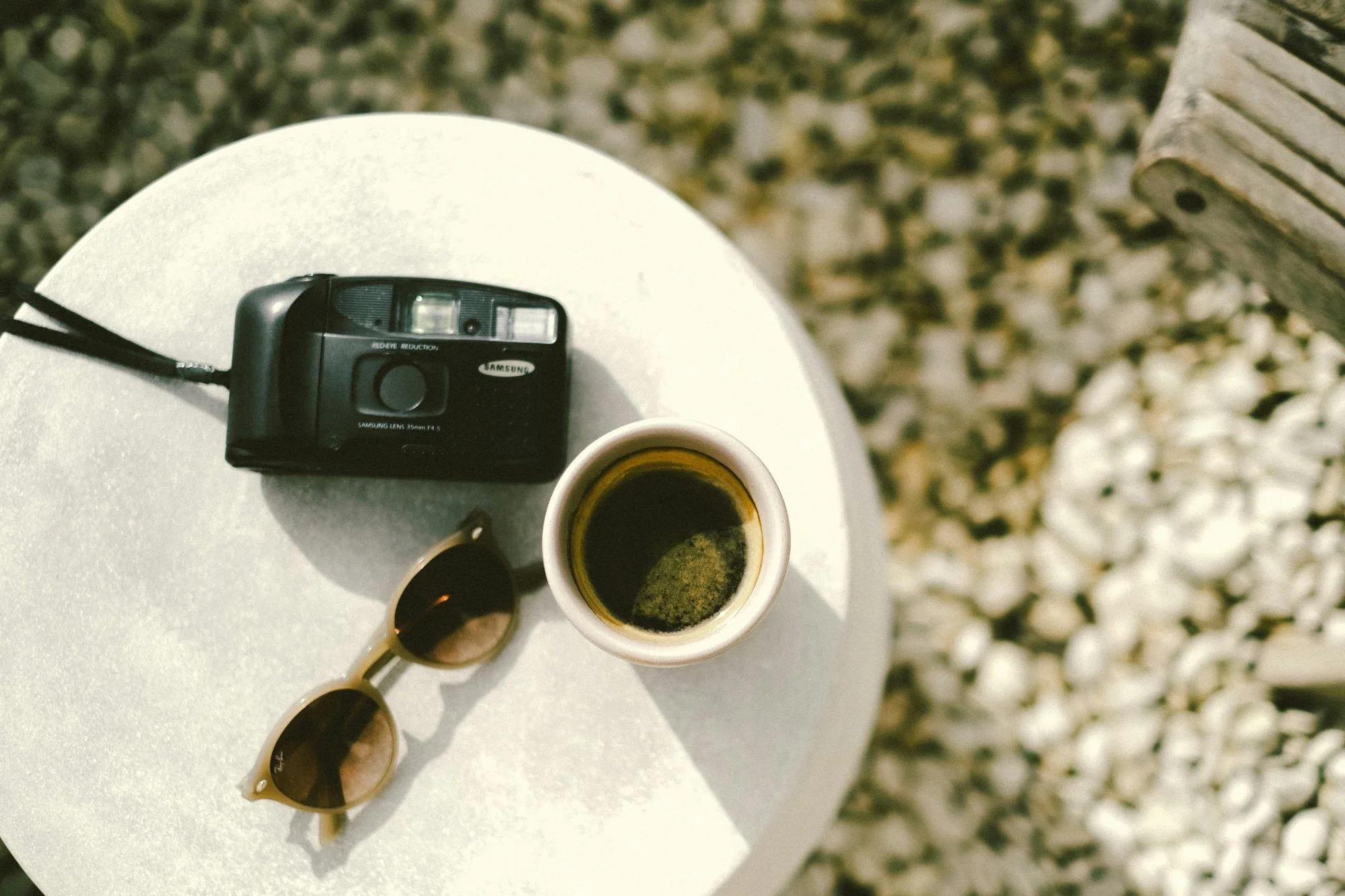 Appareil photo, lunettes de soleil et café posés sur une table