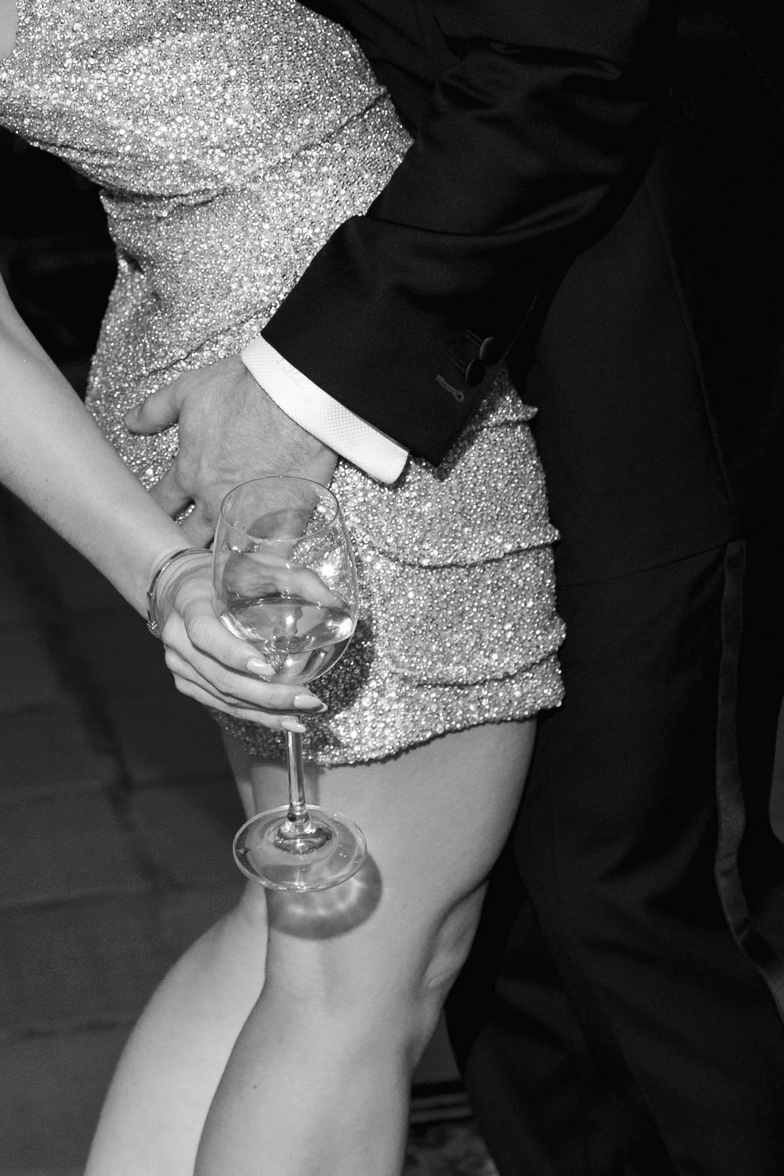 Detail of groom pulling bride in and her wine glass in hand