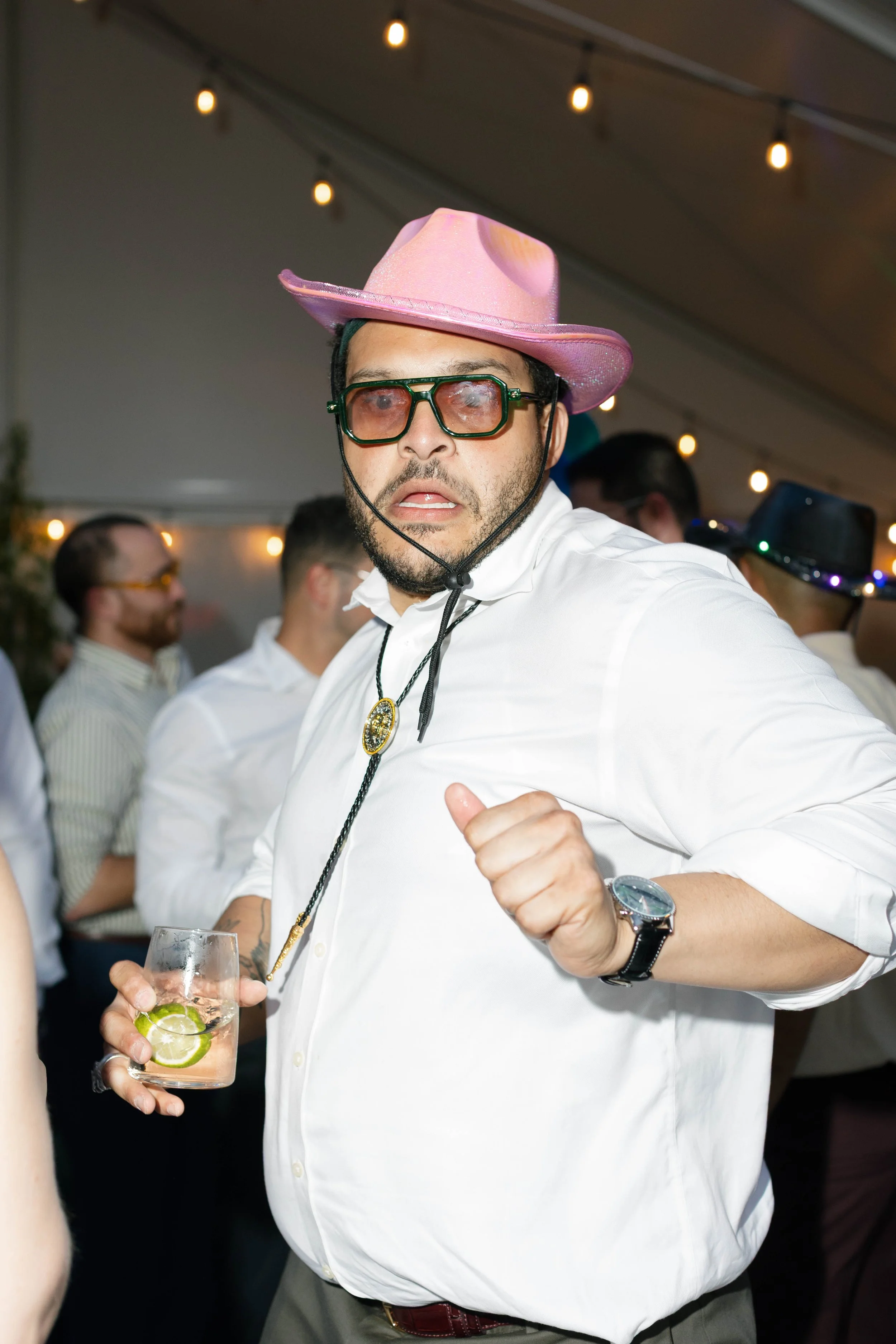 A wedding guest holding a drink and wearing a cowboy hat at reception in the tent at the Griffin House in The Gorge Oregon