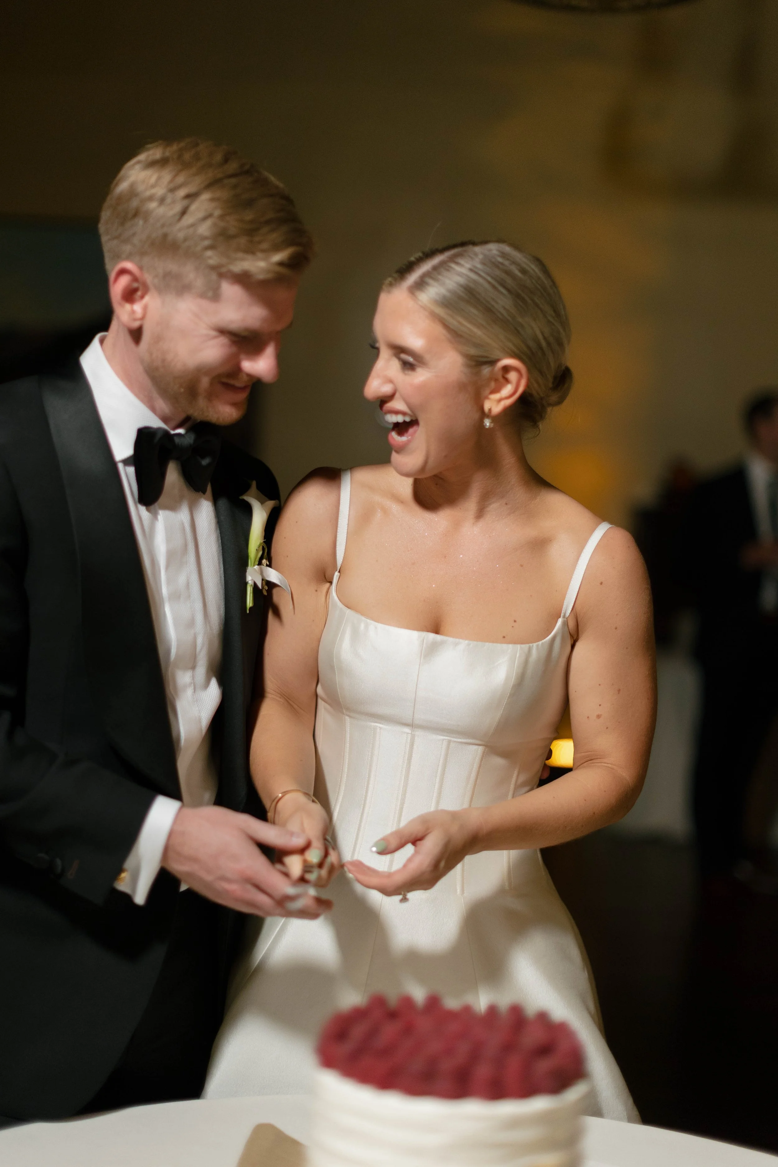 Bride and Groom laughing while cutting their cake