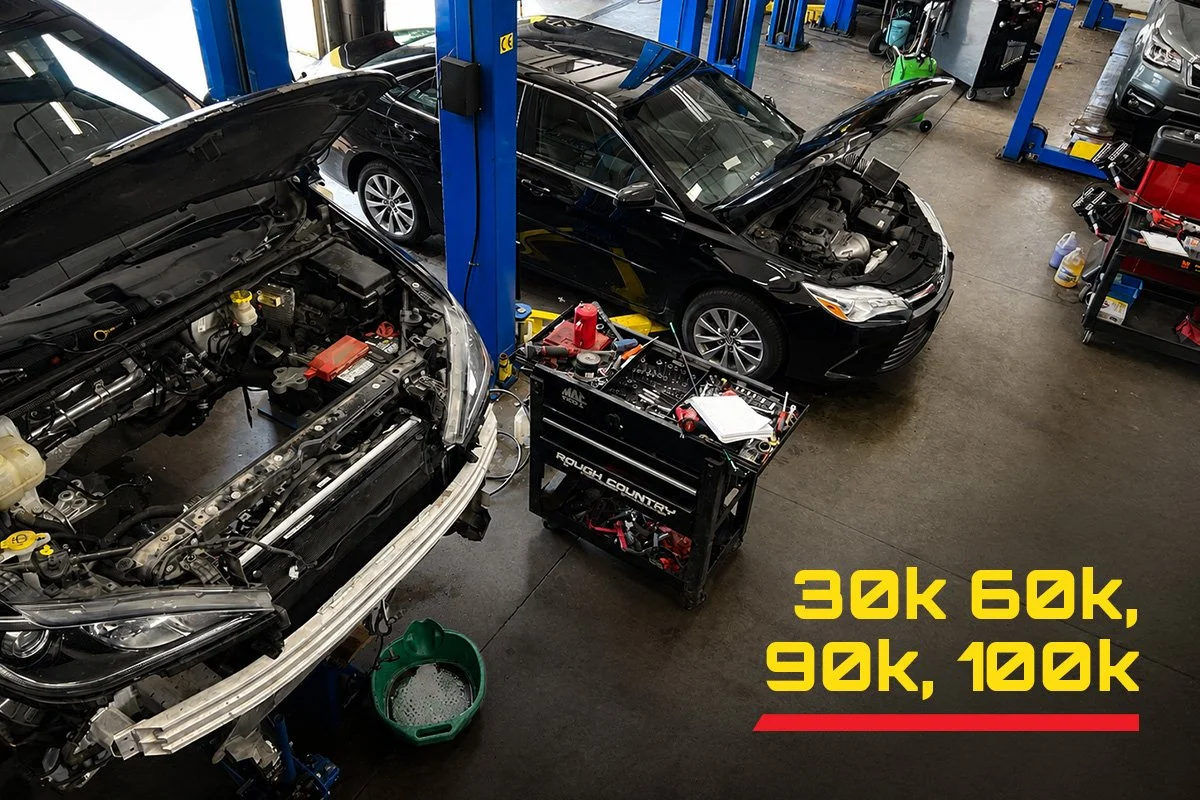 Interior of the Total Auto Care garage filled with cars with popped hoods. Text overlay reads "30k, 60k, 90k, 100k"