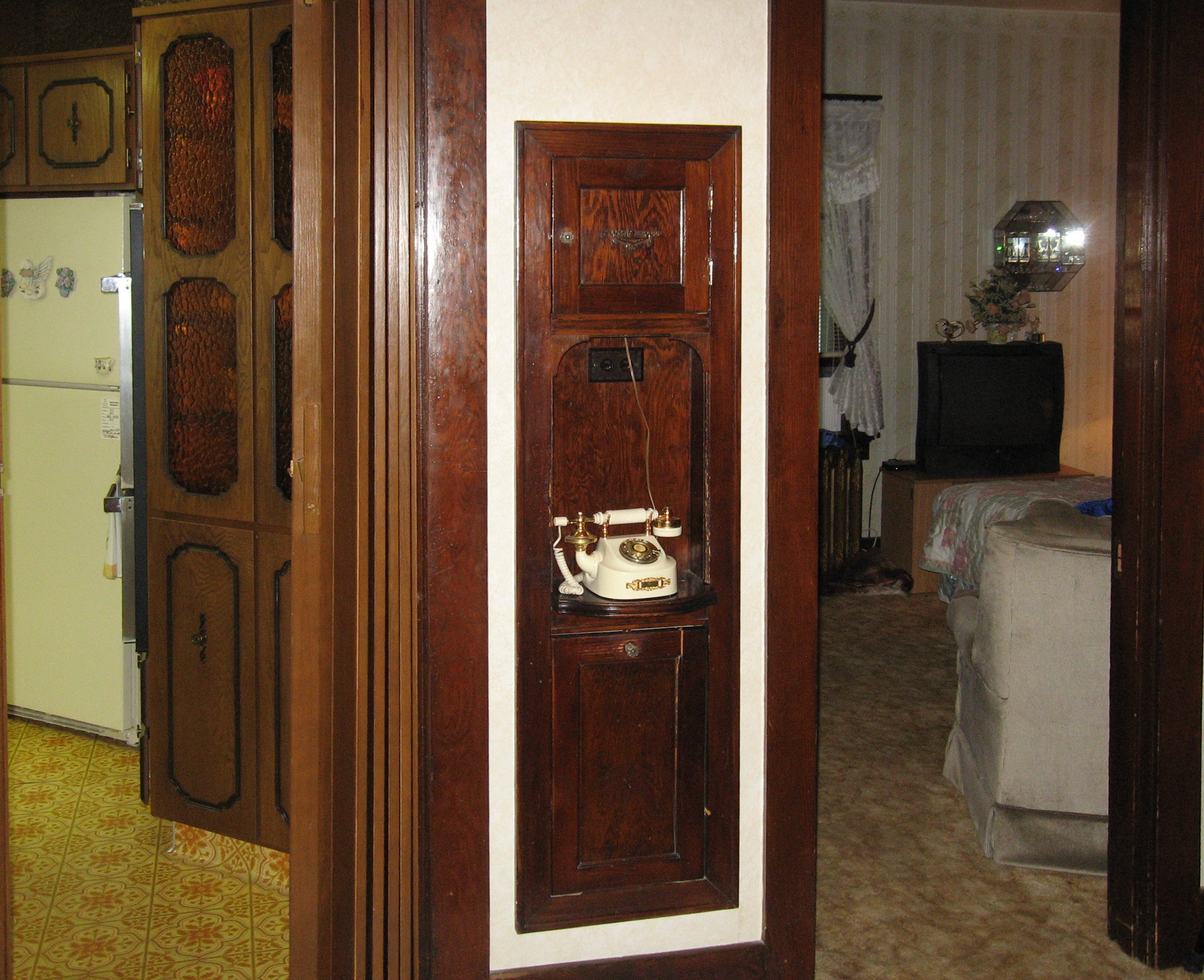 A vintage rotary telephone on a built-in wooden cabinet in a home interior.